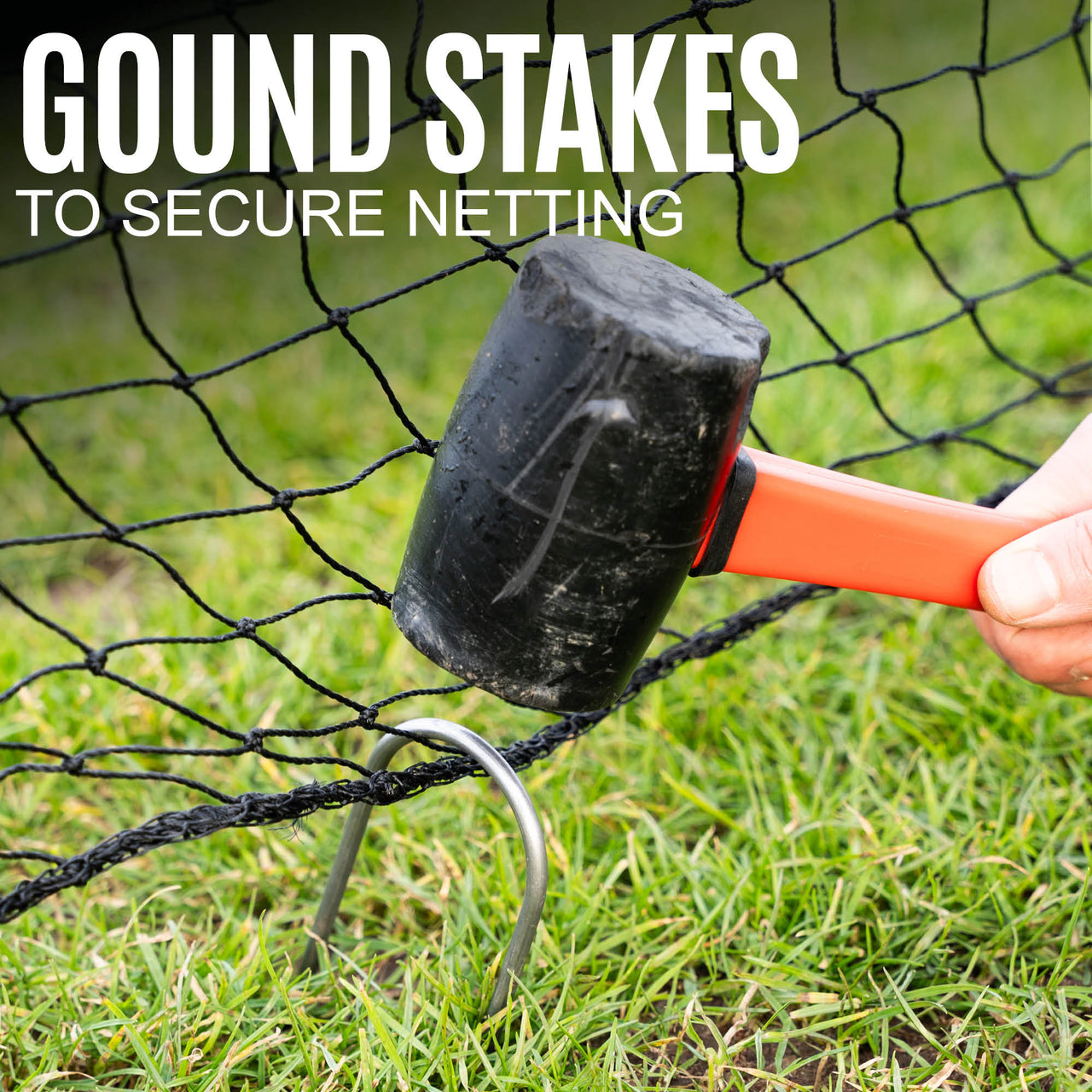 Hammering a ground stake into the grass to secure the barrier net.