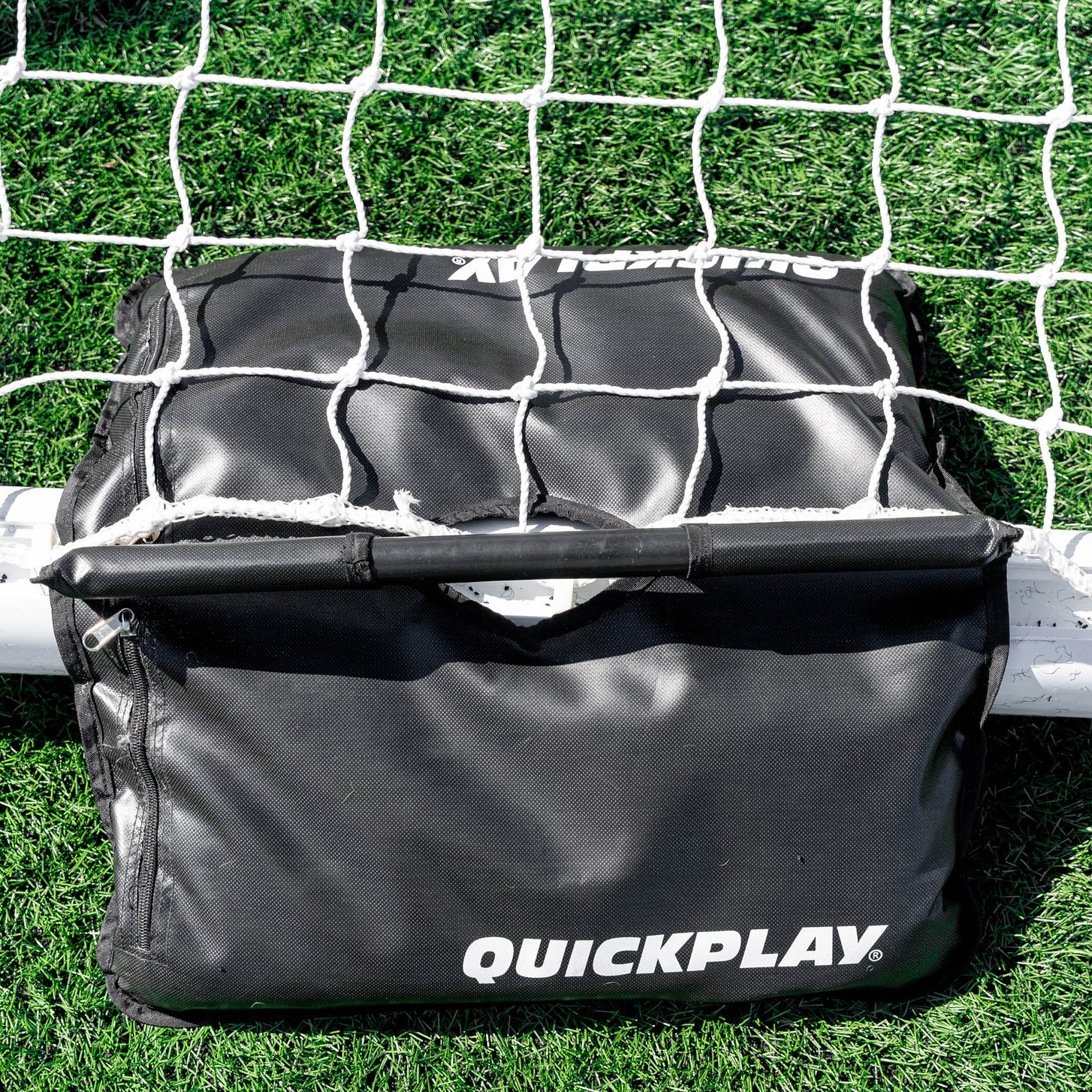 Dual Sandbag Base Weights from above, draped over the white base bar of a goal with the net lying over the top.