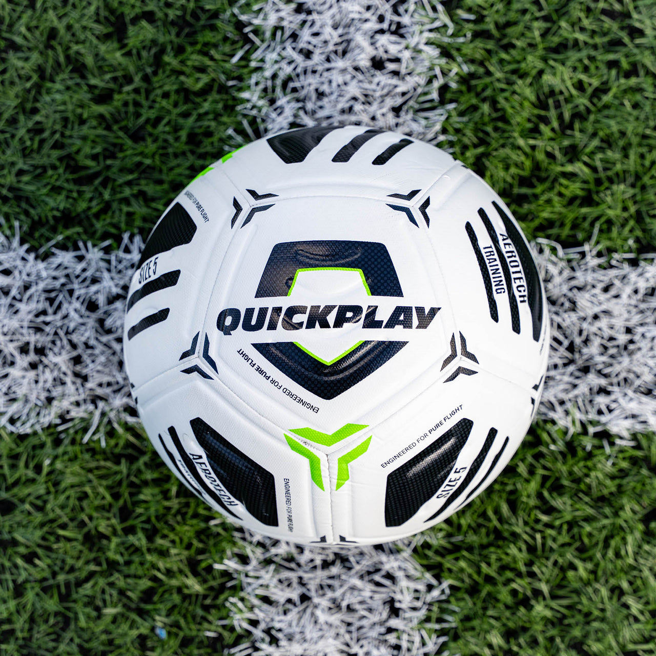 White Aerotech soccer ball with black and green accents on a grass field, featuring the brand 'Quickplay'.