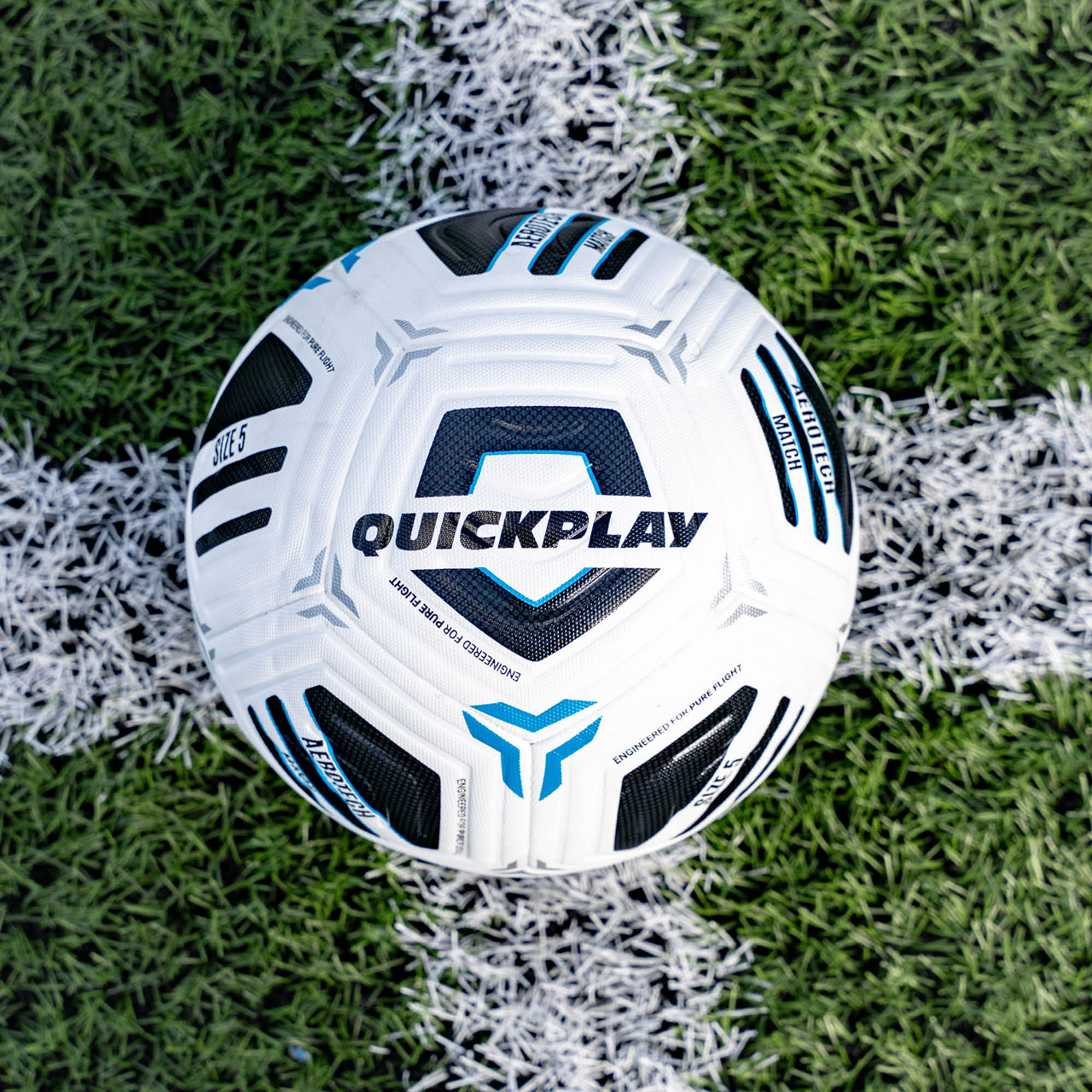 White Aerotech Match soccer ball with black and blue patterns on a grass field, featuring the 'Quickplay' brand.
