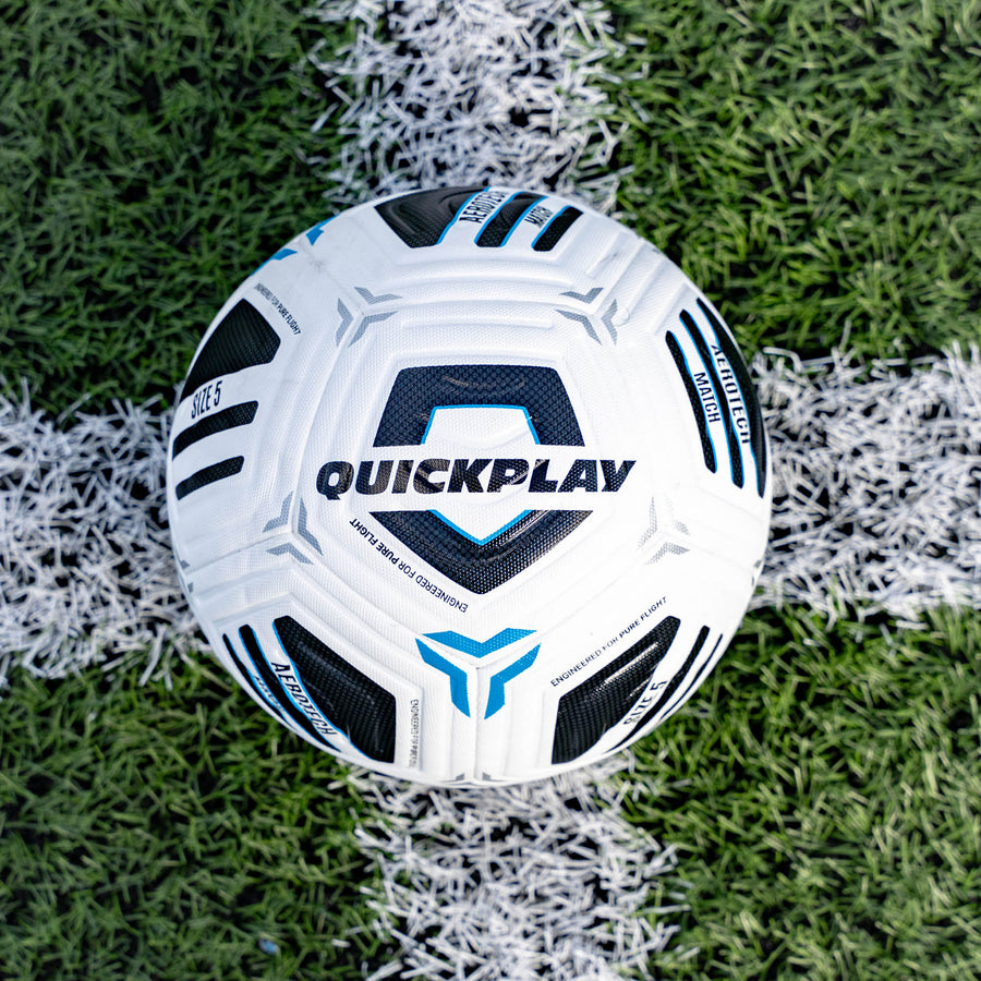 White Aerotech Match soccer ball with black and blue patterns on a grass field, featuring the 'Quickplay' brand.