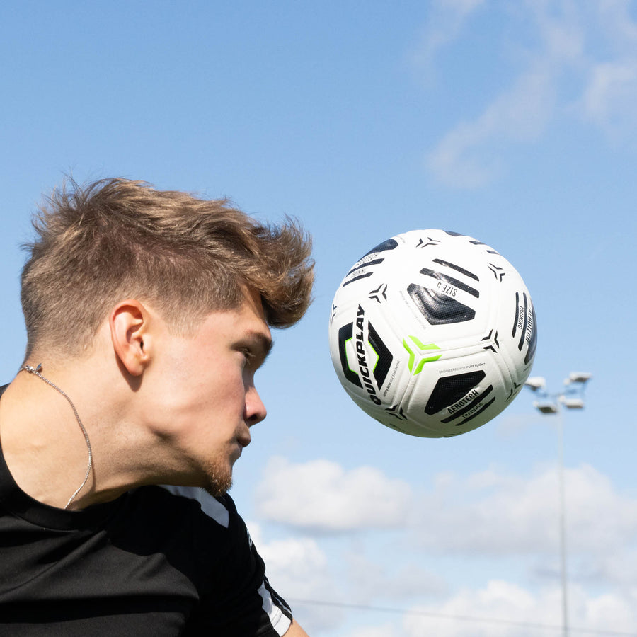 Player heading an Aerotech soccer ball with a clear blue sky in the background