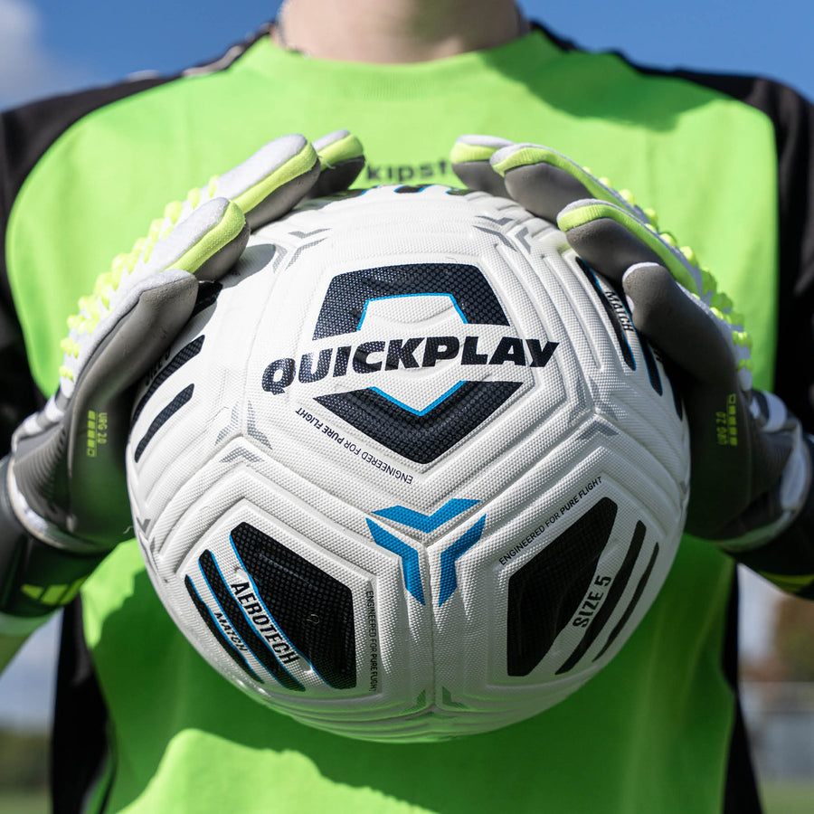 Person holding a Quickplay Aerotech Match  soccer ball with gloves on a clear day