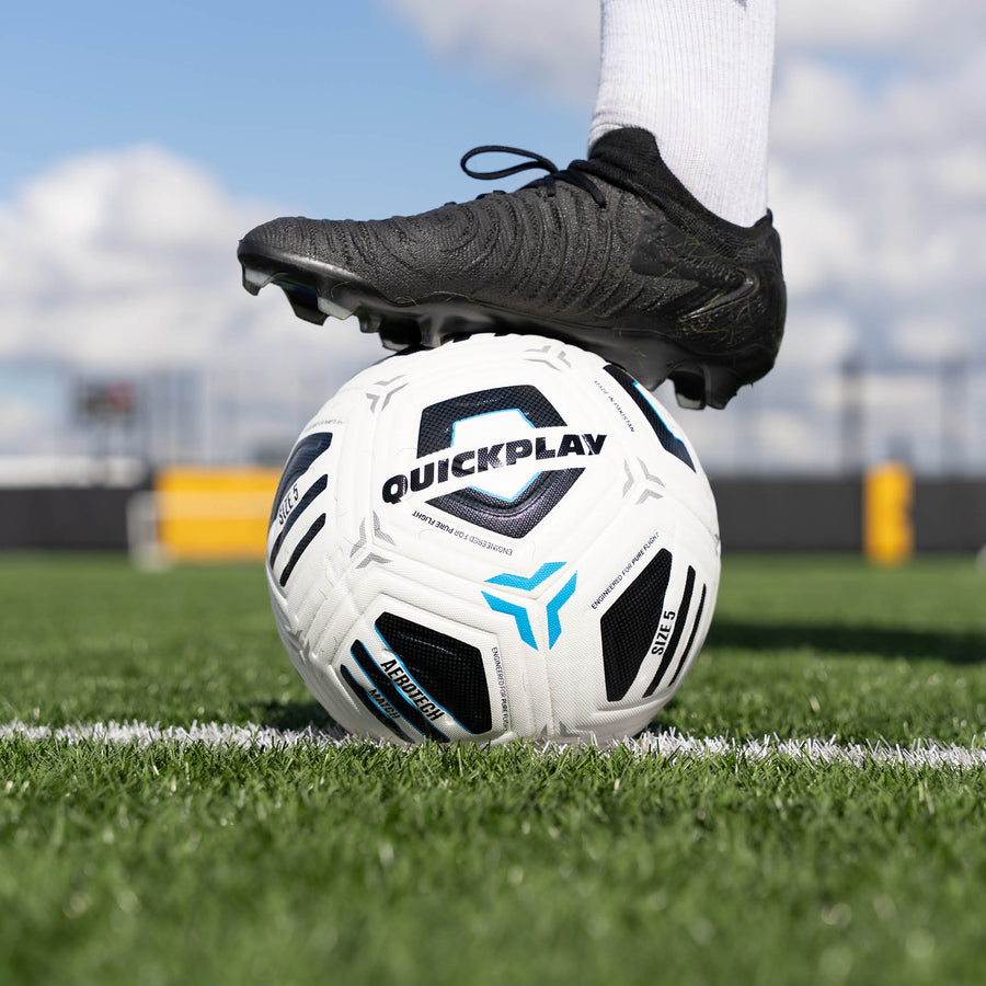 Aerotech Match Soccer ball with 'QuickPlay' branding on a grass field, foot on top