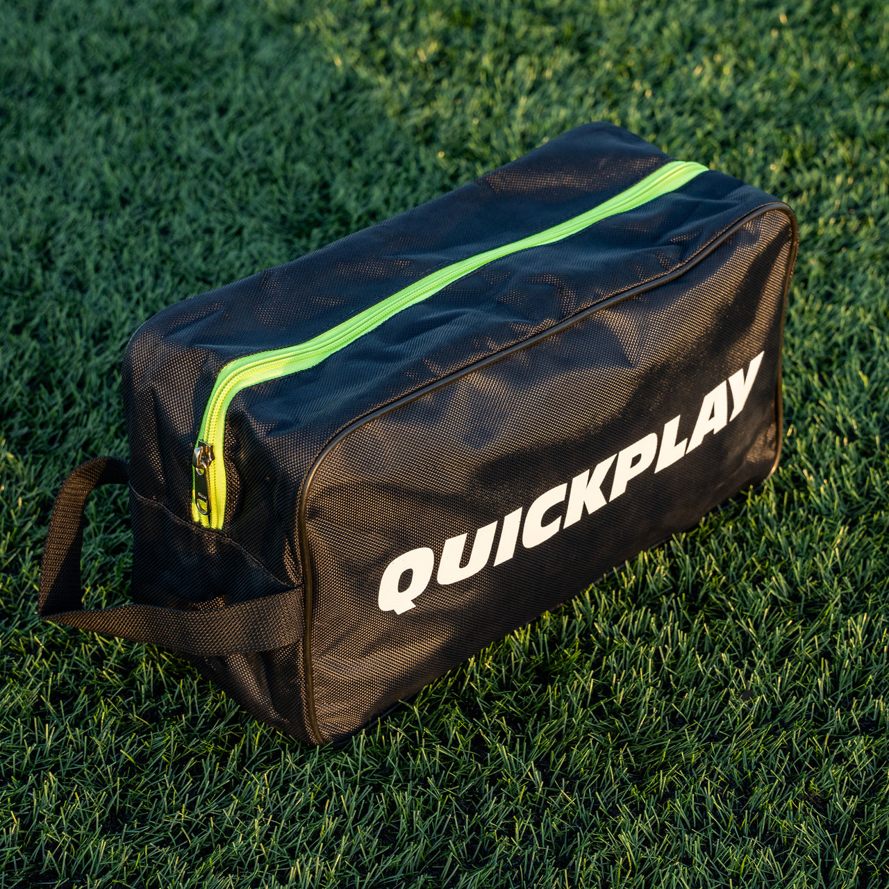 QUICKPLAY black cleat bag with green zipper on grass