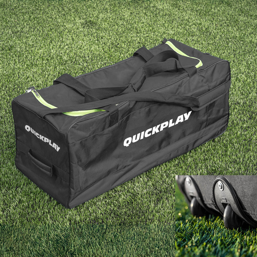 A black and green QUICKPLAY equipment bag with wheels, placed on grass.