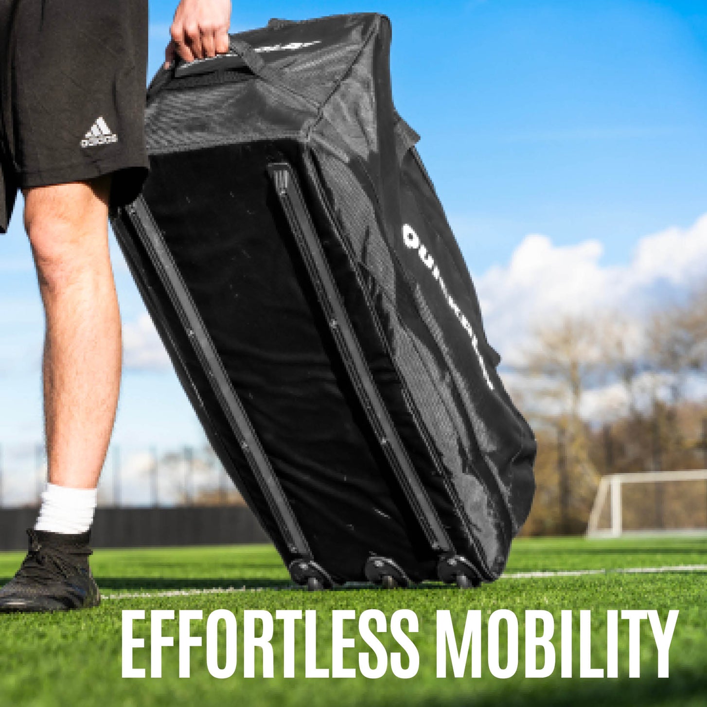 Player pulling the Equipment Bag with Wheels (XL) upright on its wheels across an artificial field, with the text "Effortless mobility".