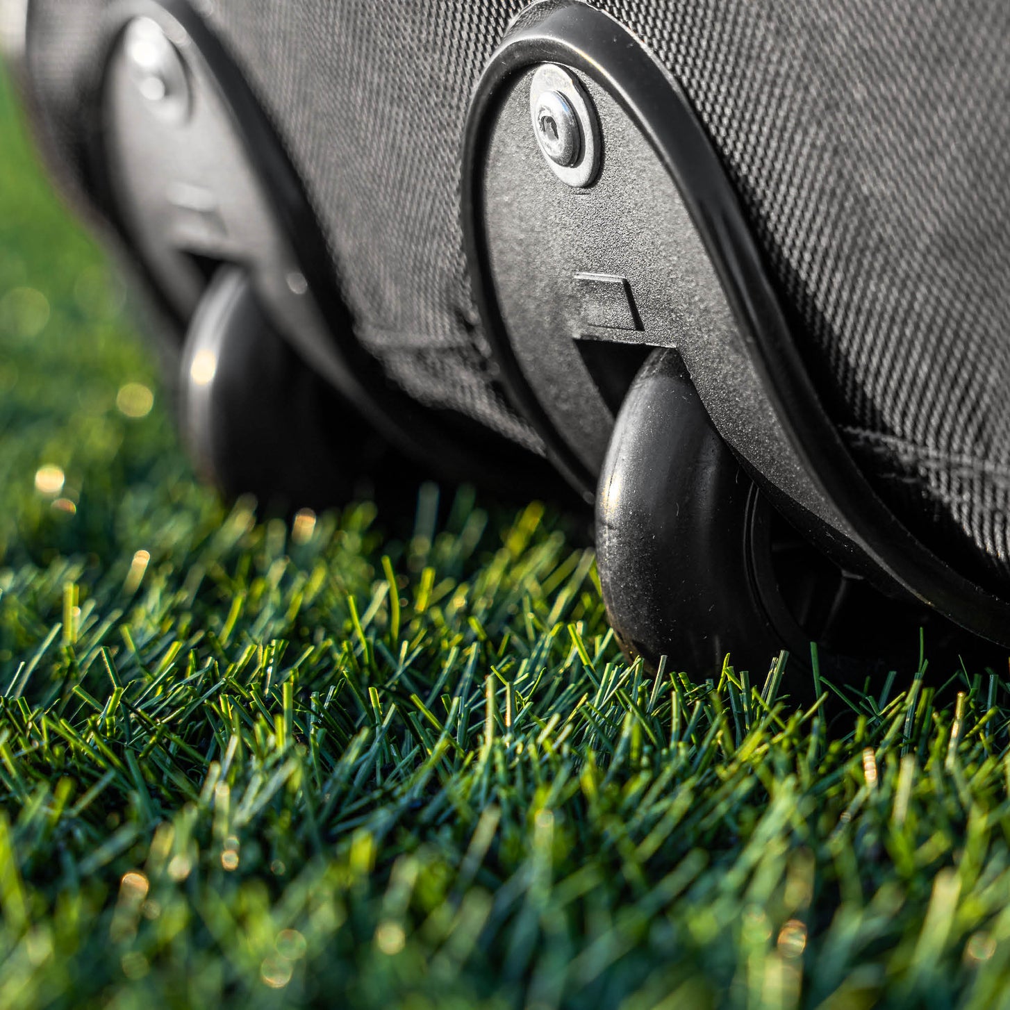 Equipment Bag with Wheels (XL): close-up of the black wheels at the base of the bag, resting on artificial turf.