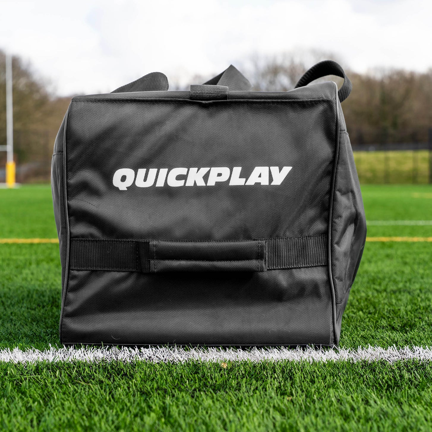 Equipment Bag with Wheels (XL) end view showing the QUICKPLAY logo and carry handle, on an artificial field.