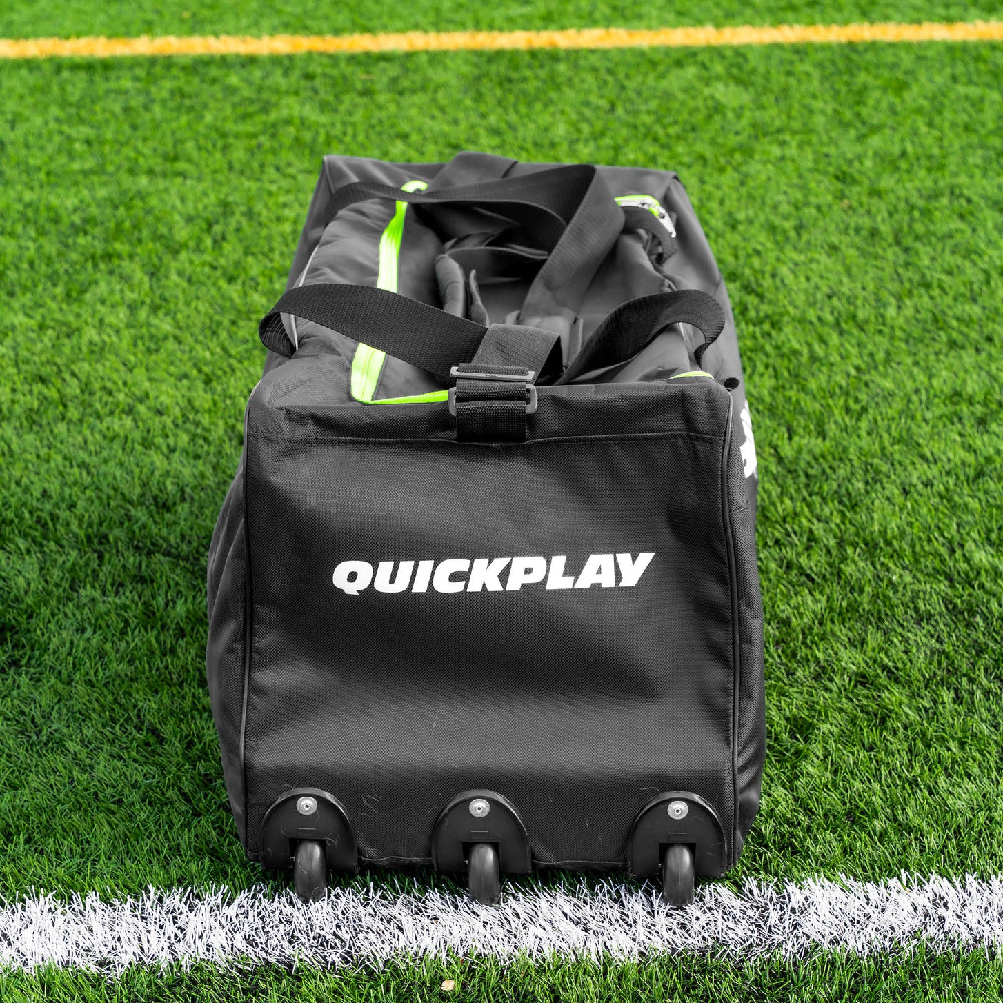 Equipment Bag with Wheels (XL) end view on artificial turf, showing the row of wheels and lime green zipper trim.