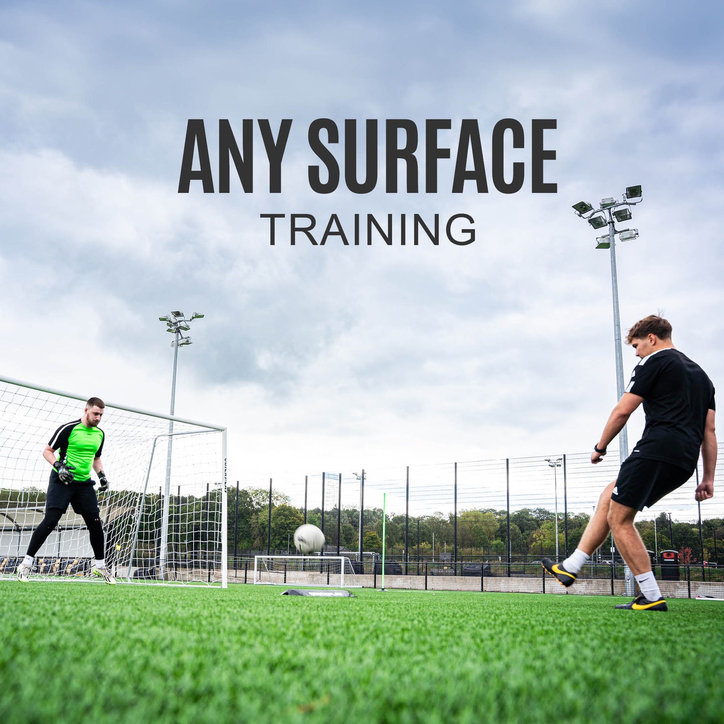Goalkeeper Deflection Ramp in front of a goal as a player shoots at the goalkeeper on an artificial field, with the text "Any surface training".