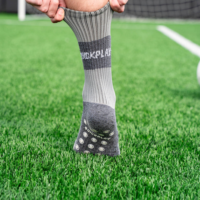 Gray grip sock with QUICKPLAY logo on grassy field