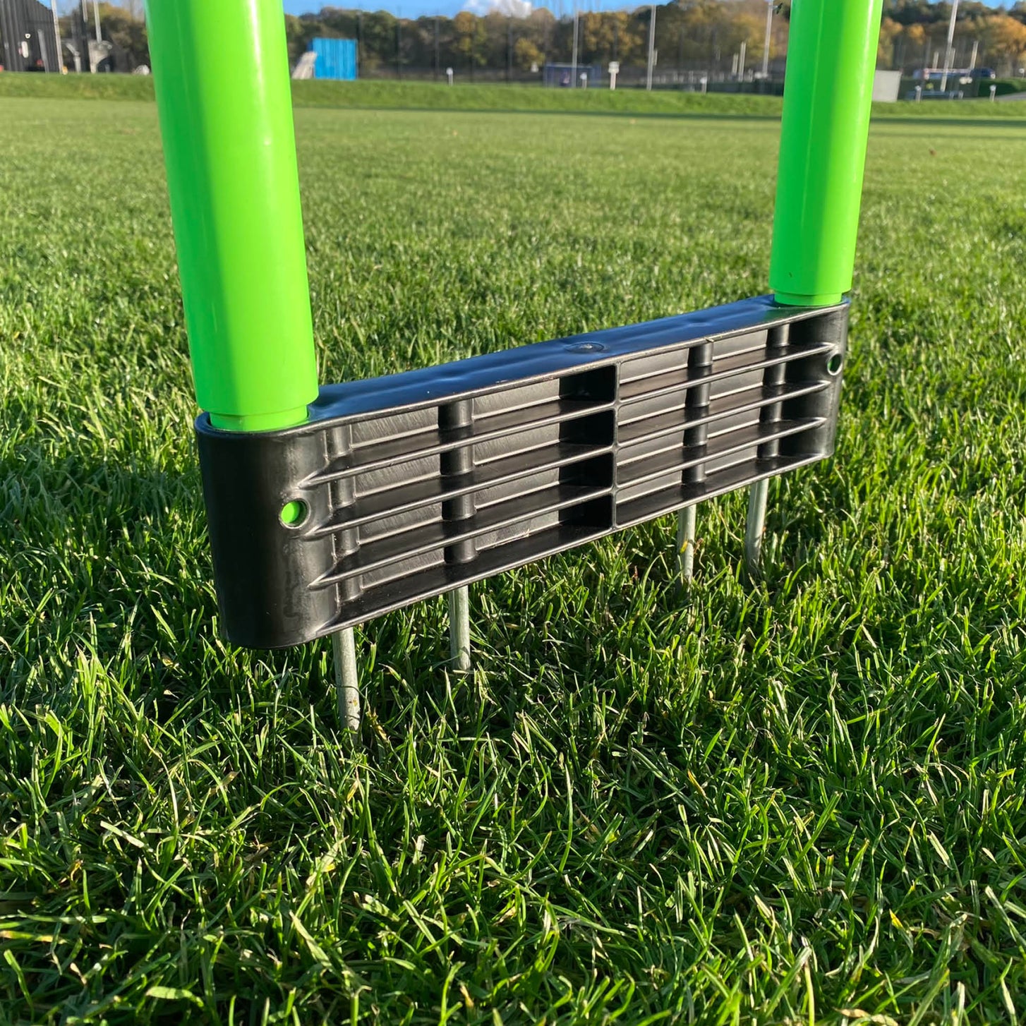 REPLAY Defender Mannequin close up: the black base on grass with its metal spikes pushed into the ground below the green legs.