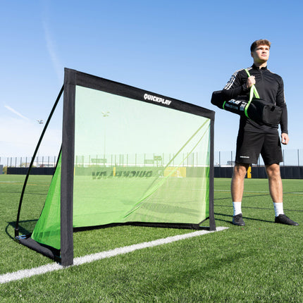Person holding a soccer training goal on a soccer field
