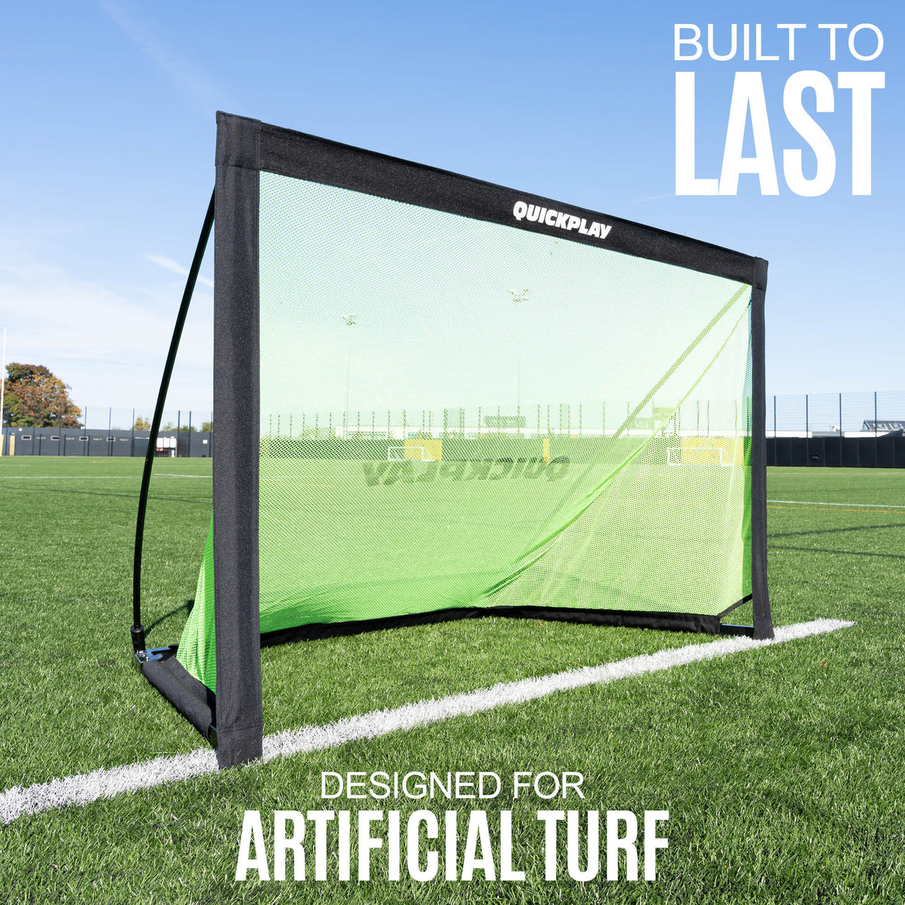 Green sports training goal with 'QuickPlay' branding on artificial turf, against a clear blue sky.