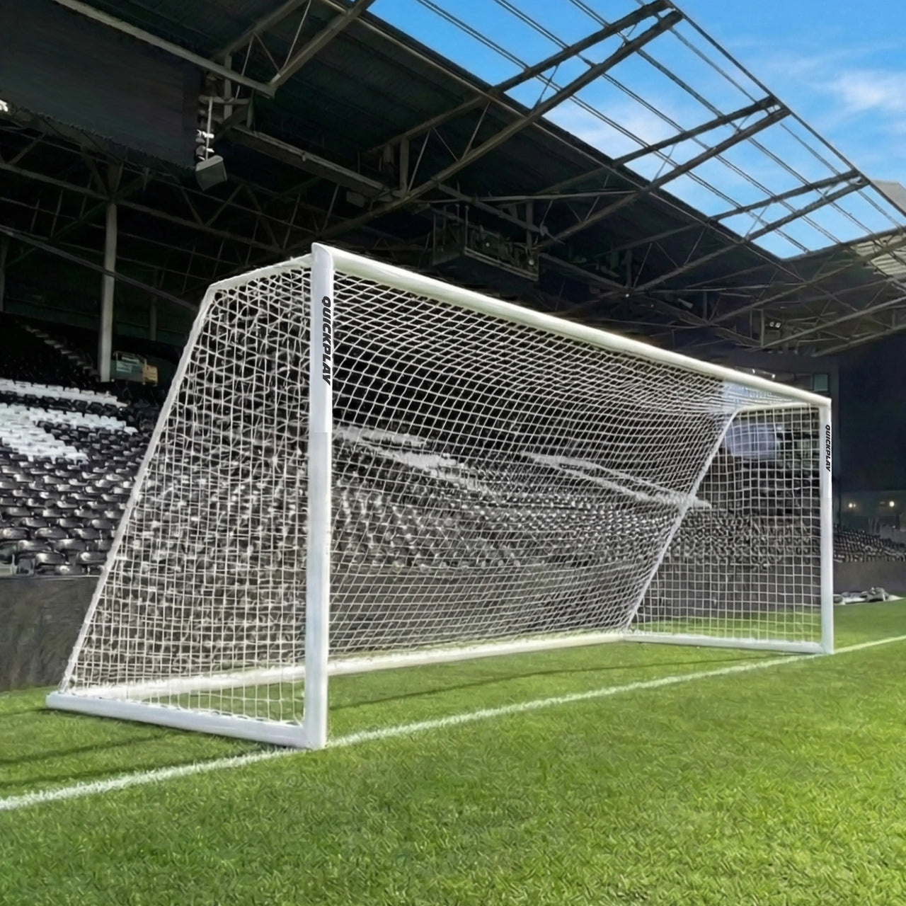QUICKPLAY Soccer goal on a grass field with stadium seats and roof in the background