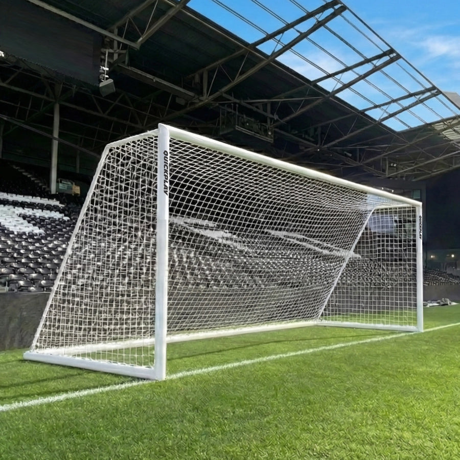 QUICKPLAY Soccer goal on a grass field with stadium seats and roof in the background