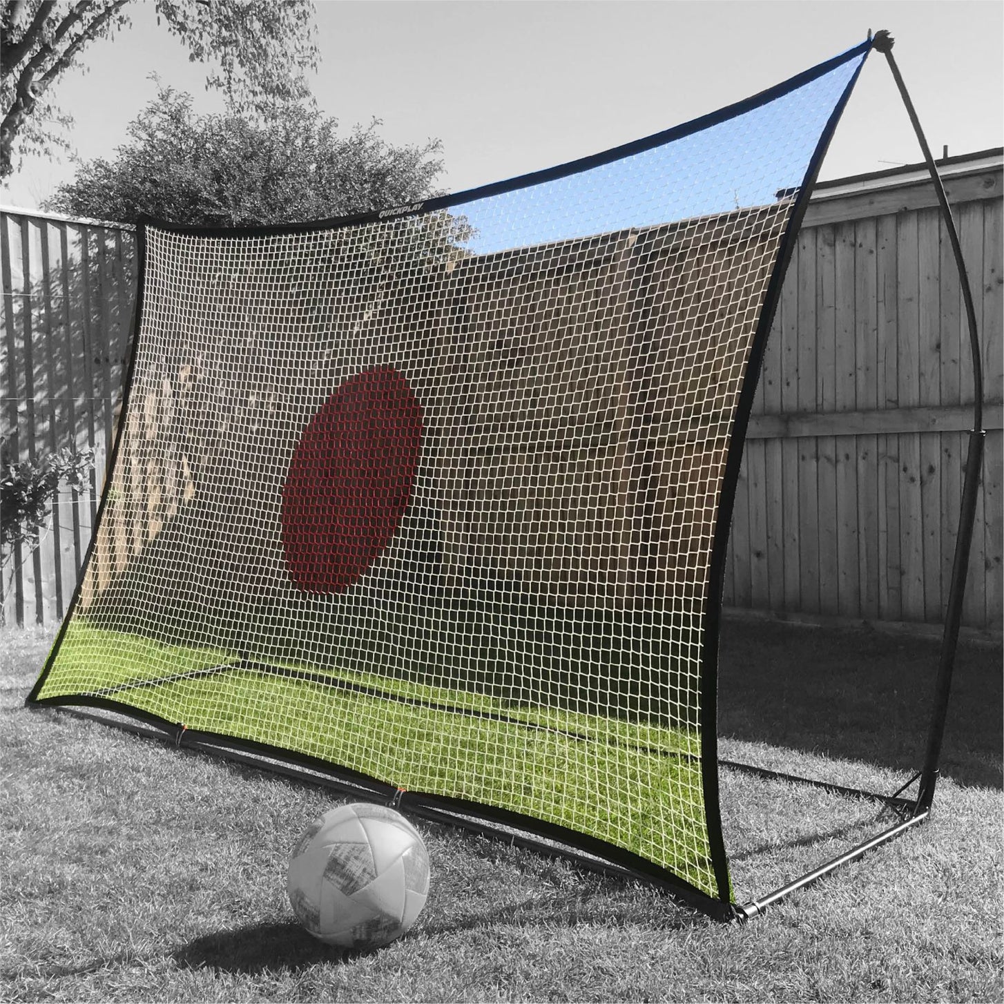 SPOT Rebounder 8x5' net with its red target spot, set up in a backyard with a soccer ball in front.