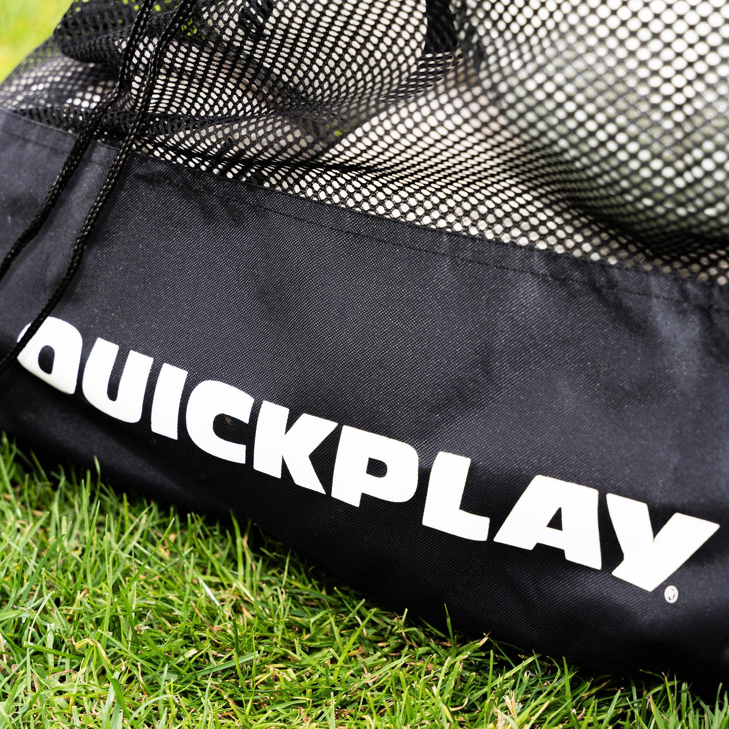 Mesh Soccer Ball Bag: close-up of the black base panel with the white QUICKPLAY logo and drawstring cord, balls visible through the mesh.
