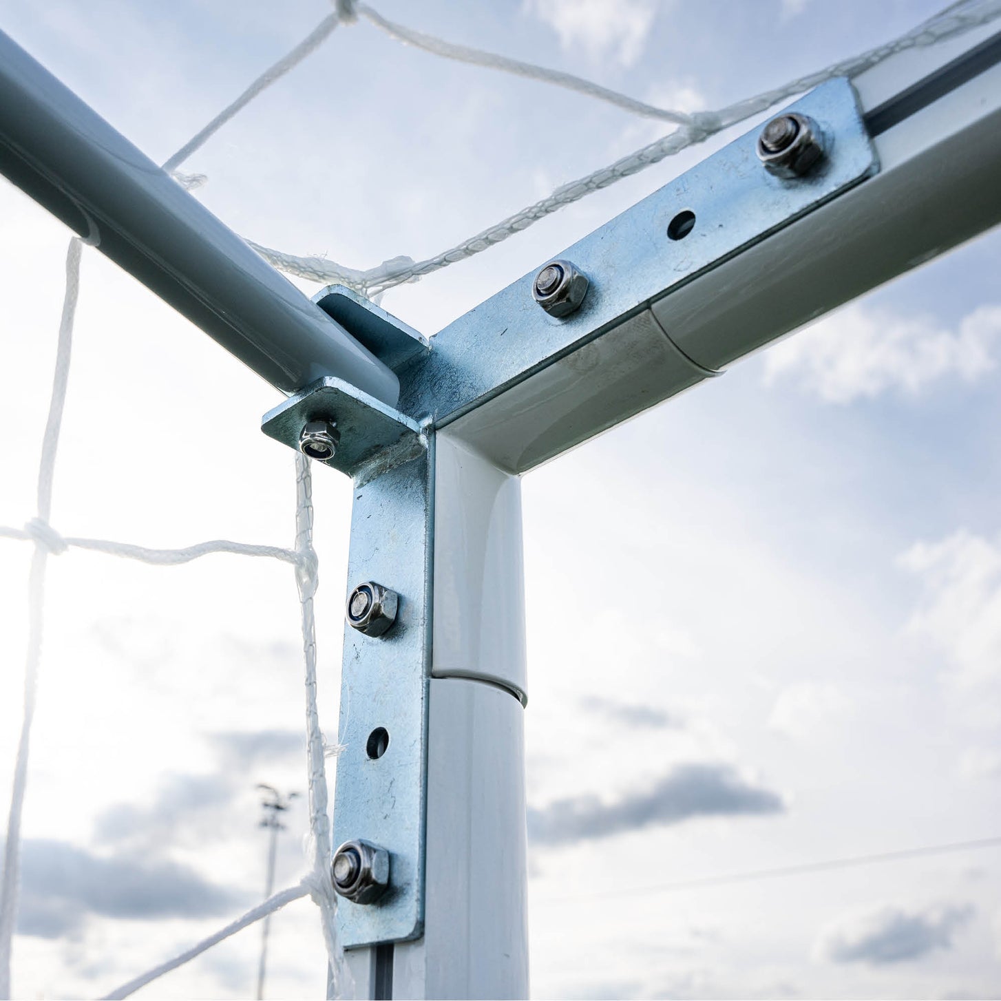 PRO ALU Match60 8x5' goal: close-up from below of the bolted metal corner bracket joining the white frame, with the net behind.