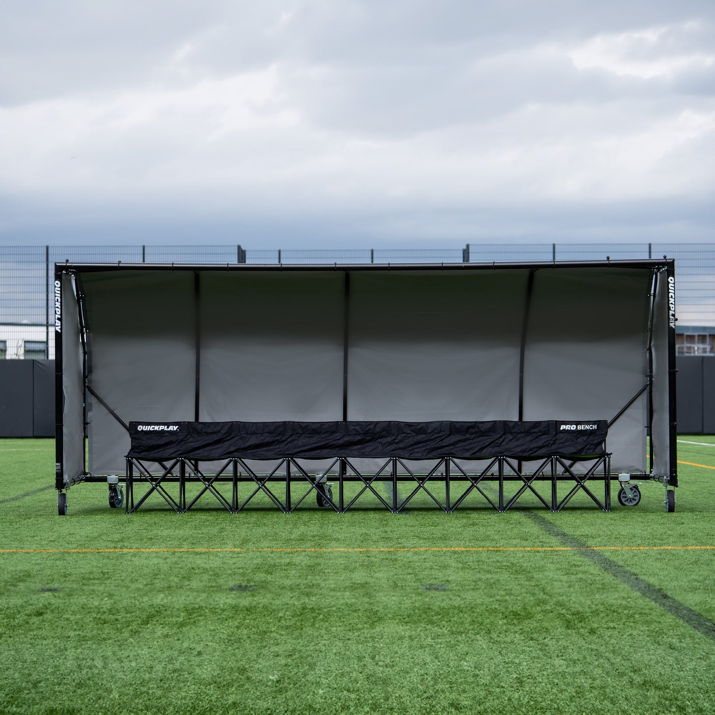 PRO ALU Club Shelter 16x6' front view on an artificial field, with a long black PRO BENCH inside.