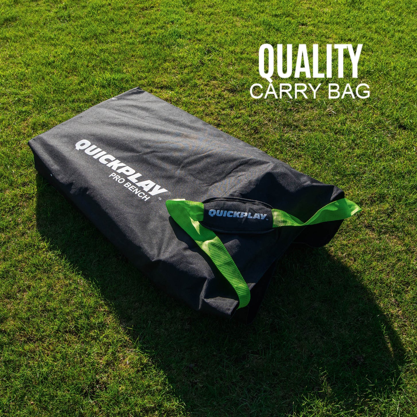 PRO Bench 4 Seat bench packed in its black QUICKPLAY PRO Bench carry bag with green handles on grass.