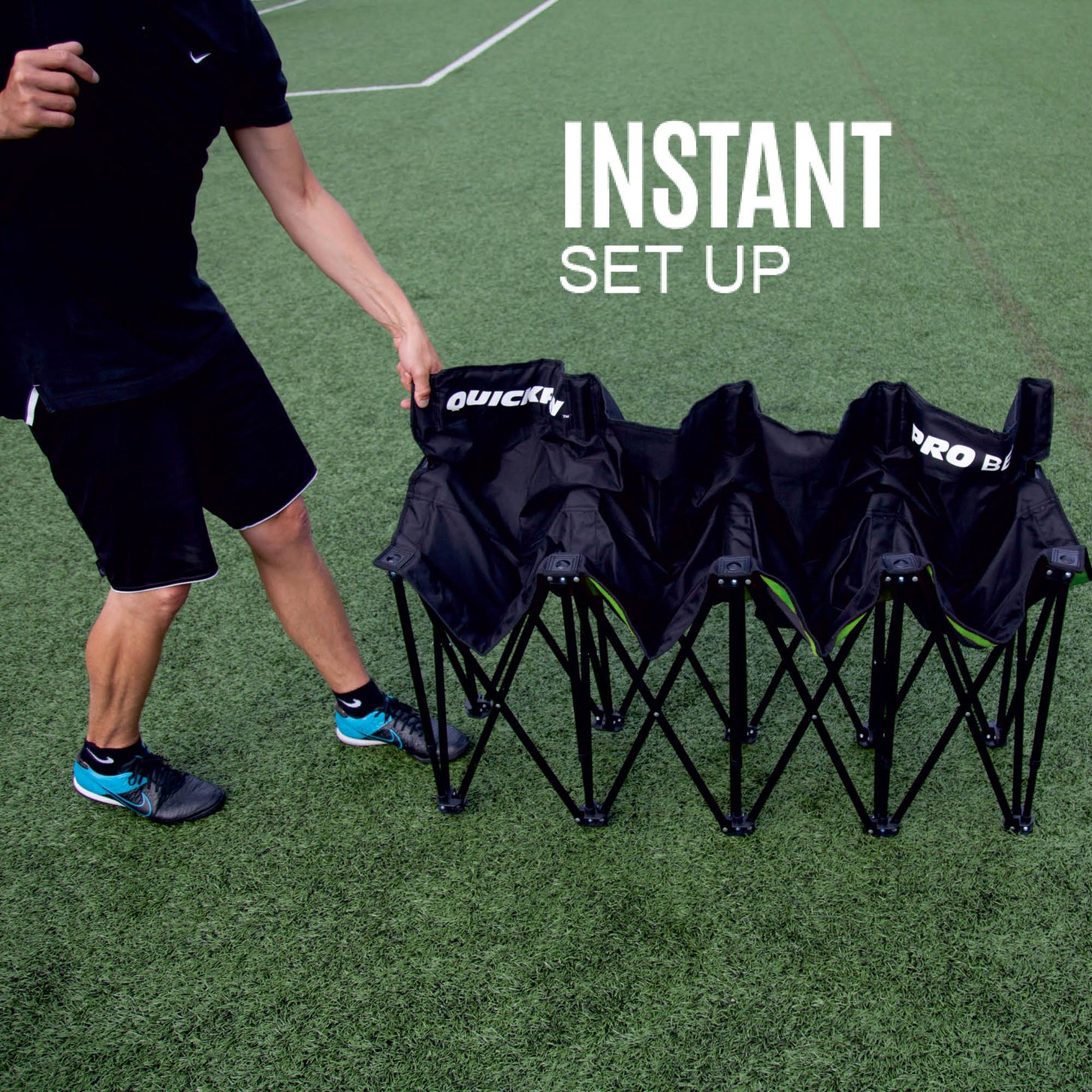 Man pulling open the PRO Bench 4 Seat bench on an artificial field, showing the black seats and folding frame.