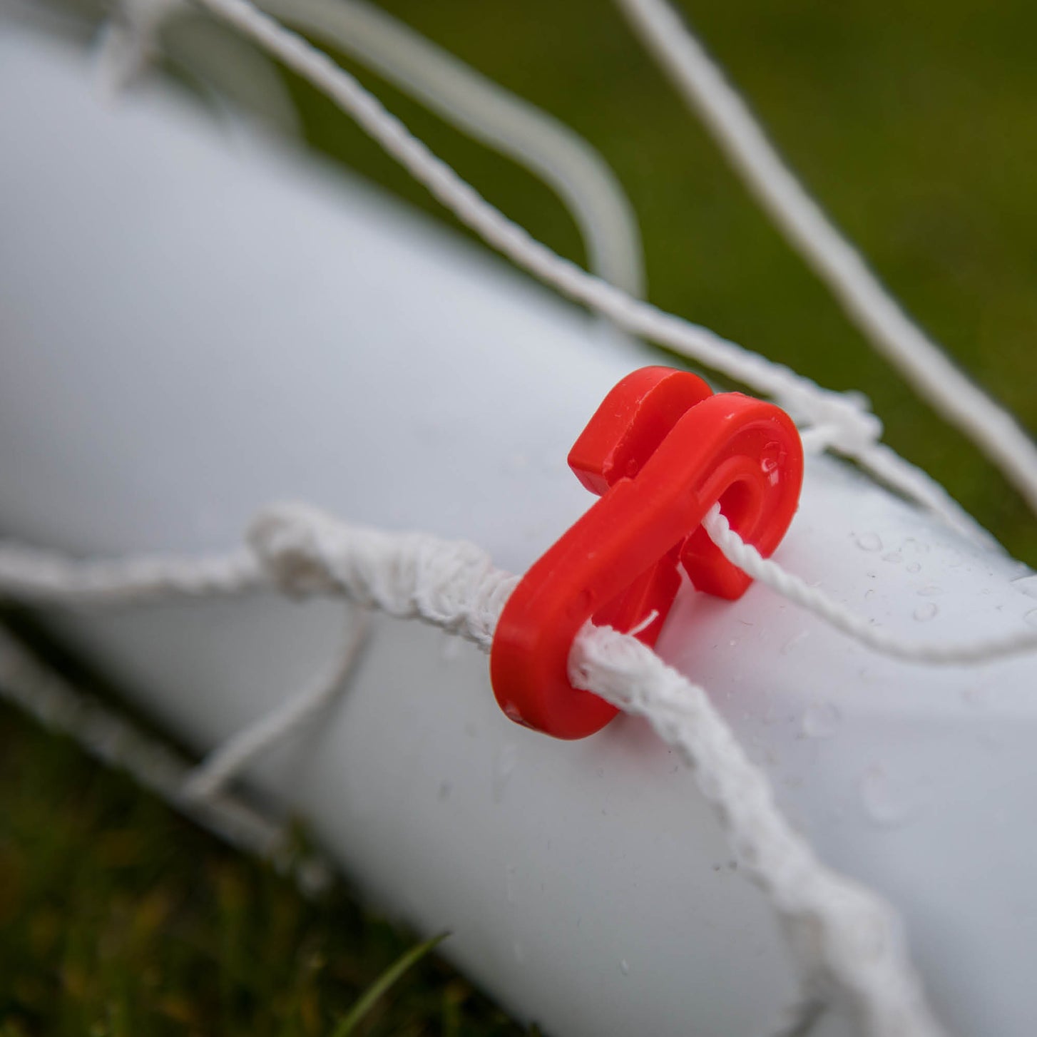 Q-FOLD Mini 3x2.5' red net hook close up, holding the white net cord on the frame.