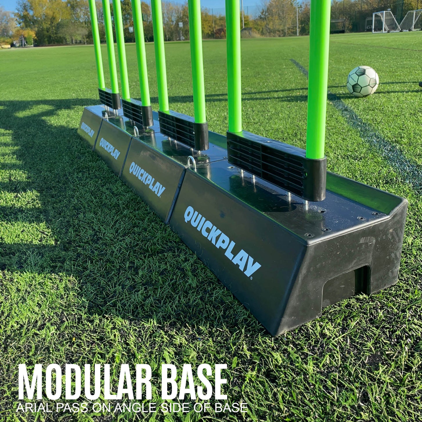 Close-up of linked black QUICKPLAY bases holding green REPLAY Defender & Block System poles, with the text "Modular base".