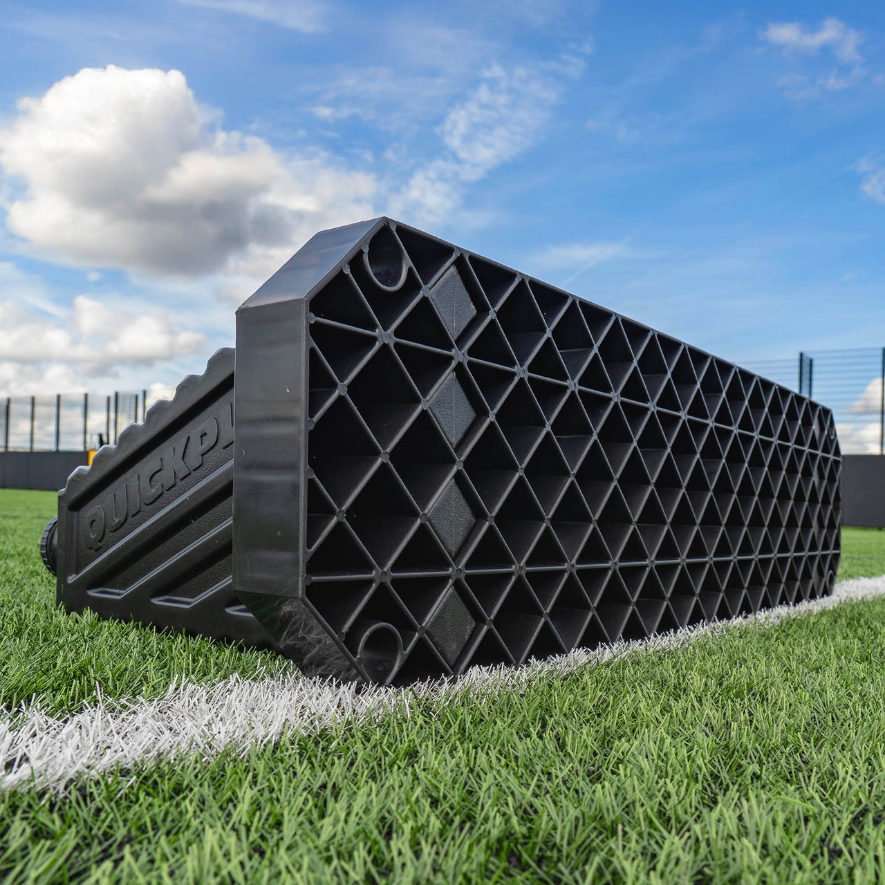 Black plastic Rebound board on a grassy field with a blue sky.