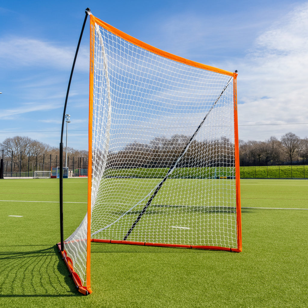 Orange sports net on a grass field with trees and sky in the background