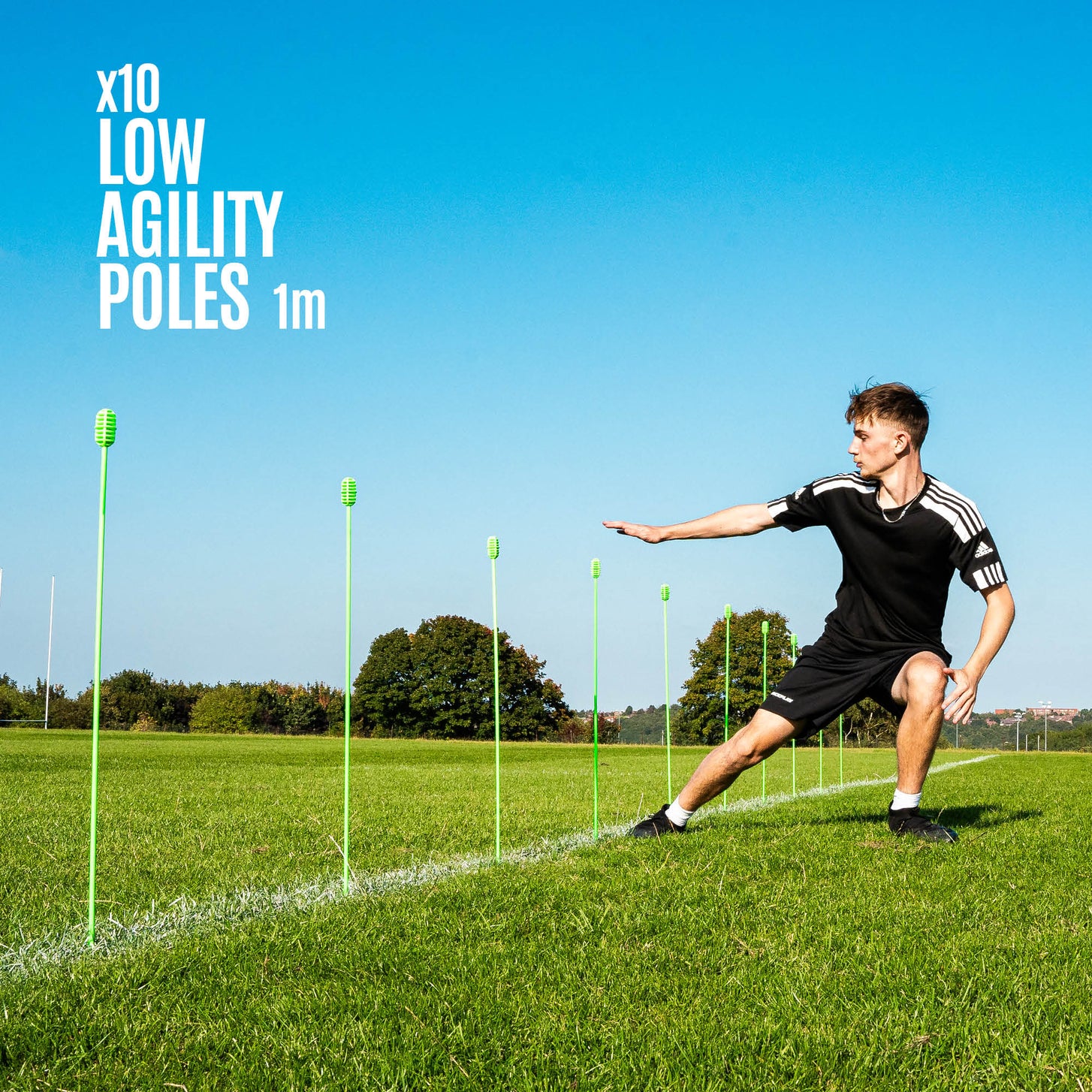 Person using QUICKPLAY agility training poles on a grass field with clear blue sky