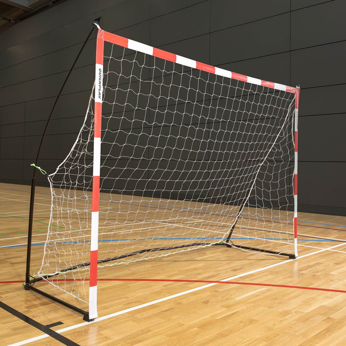 Portable Adult Handball Goal 9.8x6.5' with red and white posts standing on a wooden indoor sports hall floor.