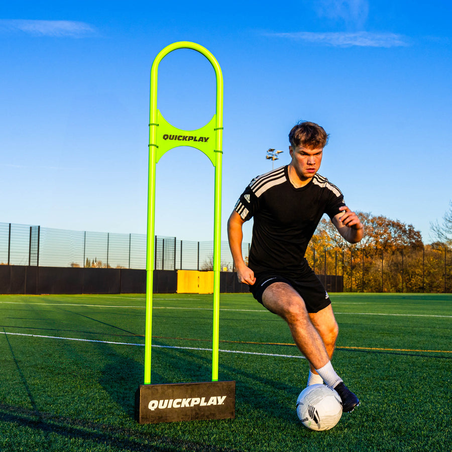 Person playing soccer on a field with a green mannequin defender post labeled 'QuickPlay'.