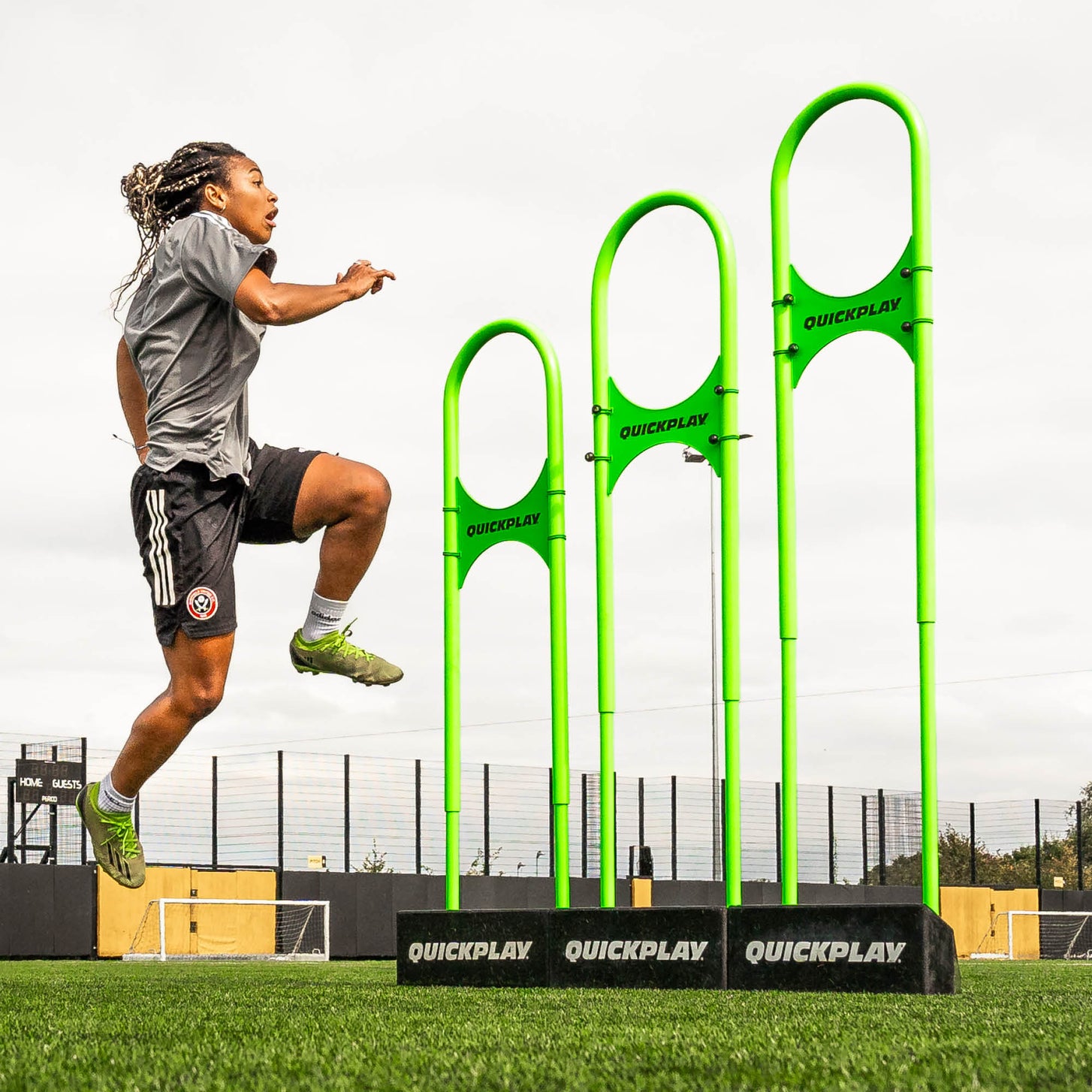 REPLAY Defender Airflow Mannequin: player jumping beside three green mannequins of rising height on artificial turf.
