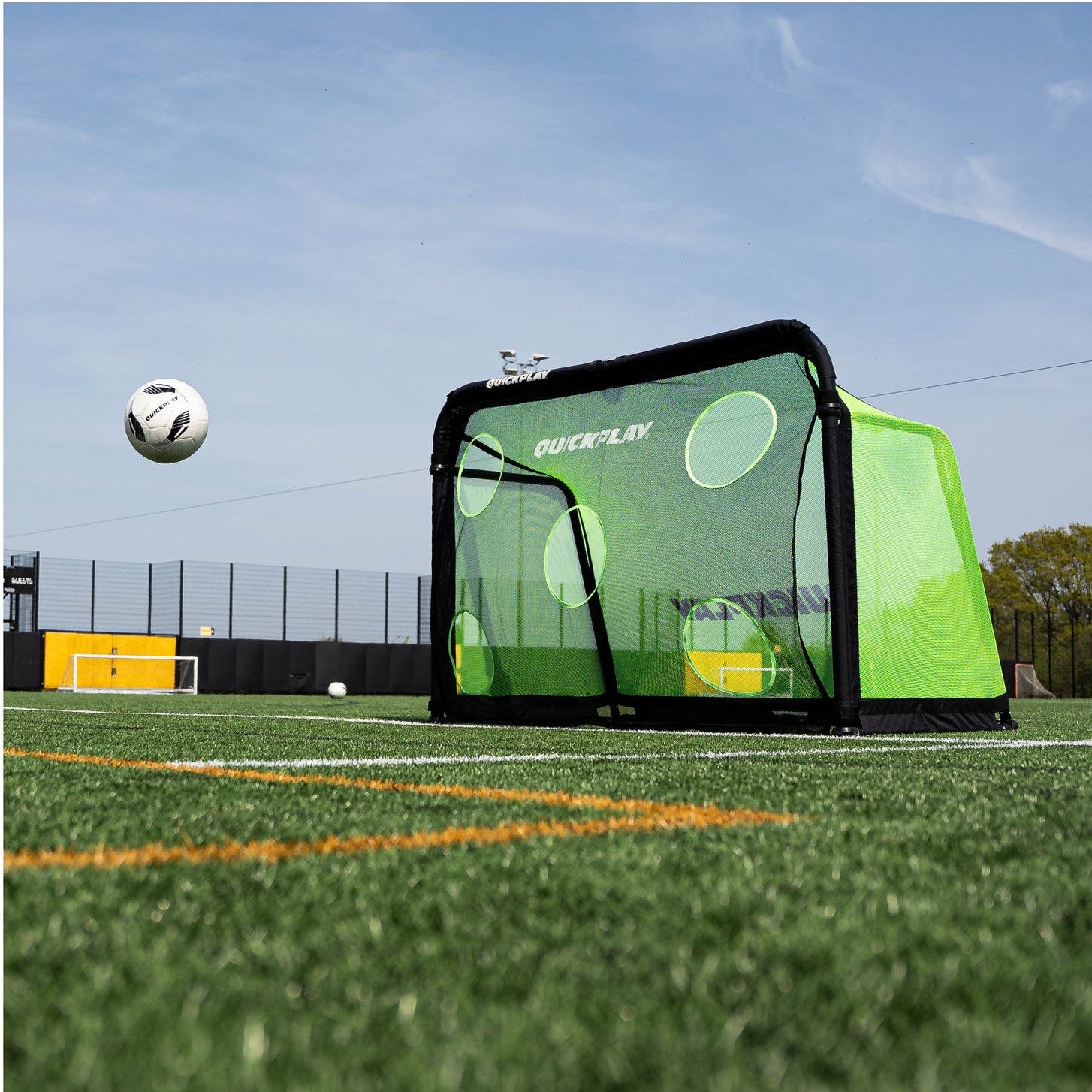 PRO ALU Training Target Net Lite 5x3' on a goal, low angle view with a soccer ball in the air on an artificial field.