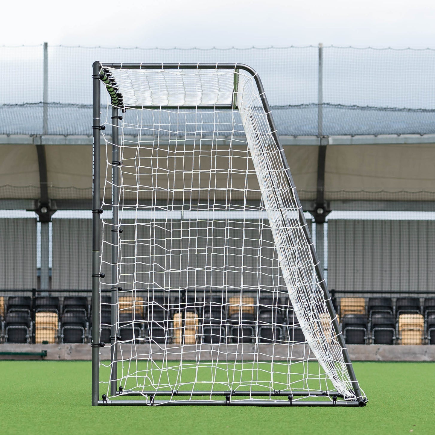 GS Series Soccer Goal 12x6' side view showing the sloped back frame and white net, in front of stadium seats.