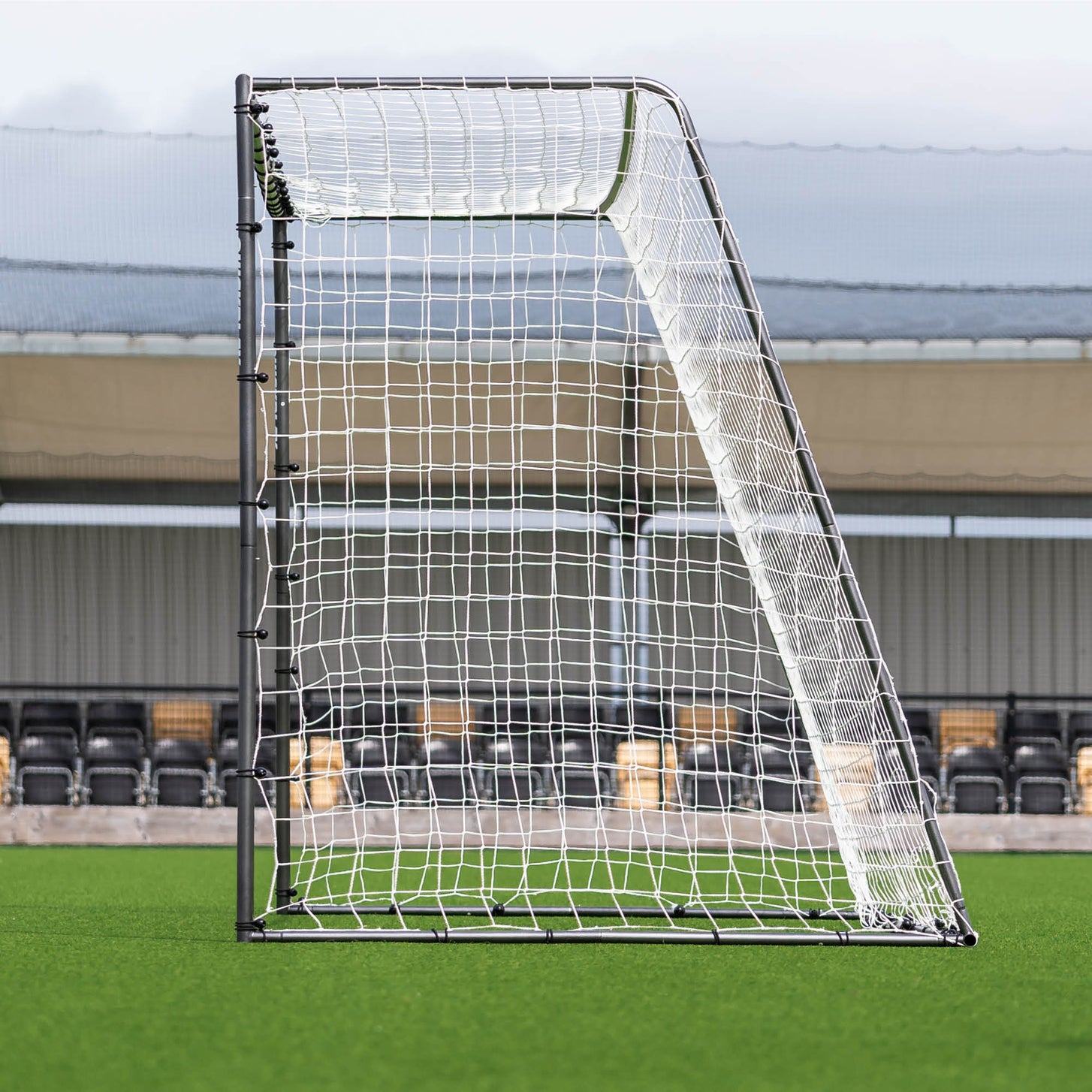 GS Series Soccer Goal 16x7' side view showing the sloped back frame and net, with stadium seats behind.
