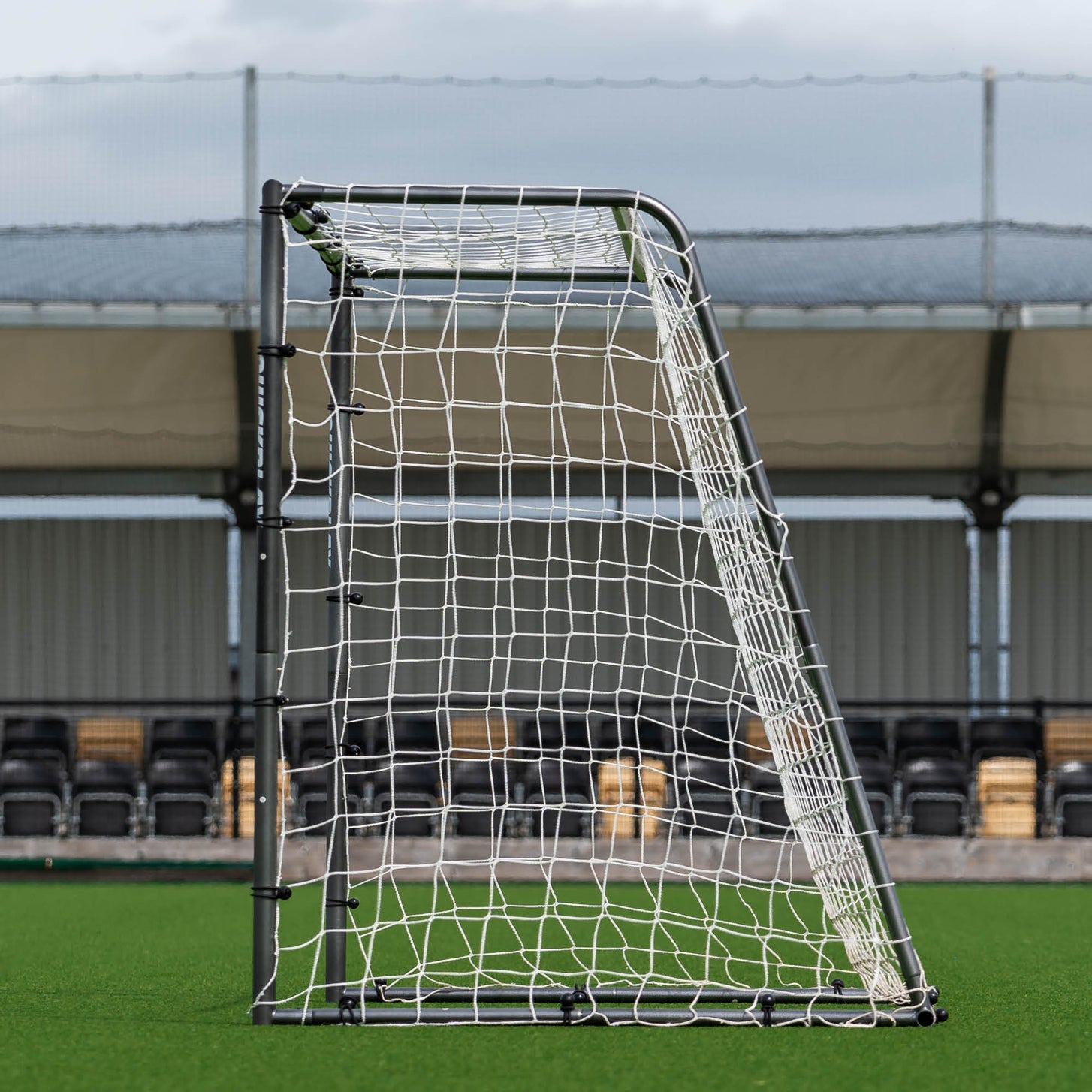 GS Series Soccer Goal 8x5' side view showing the sloped back frame that holds the net, in front of a stadium stand.