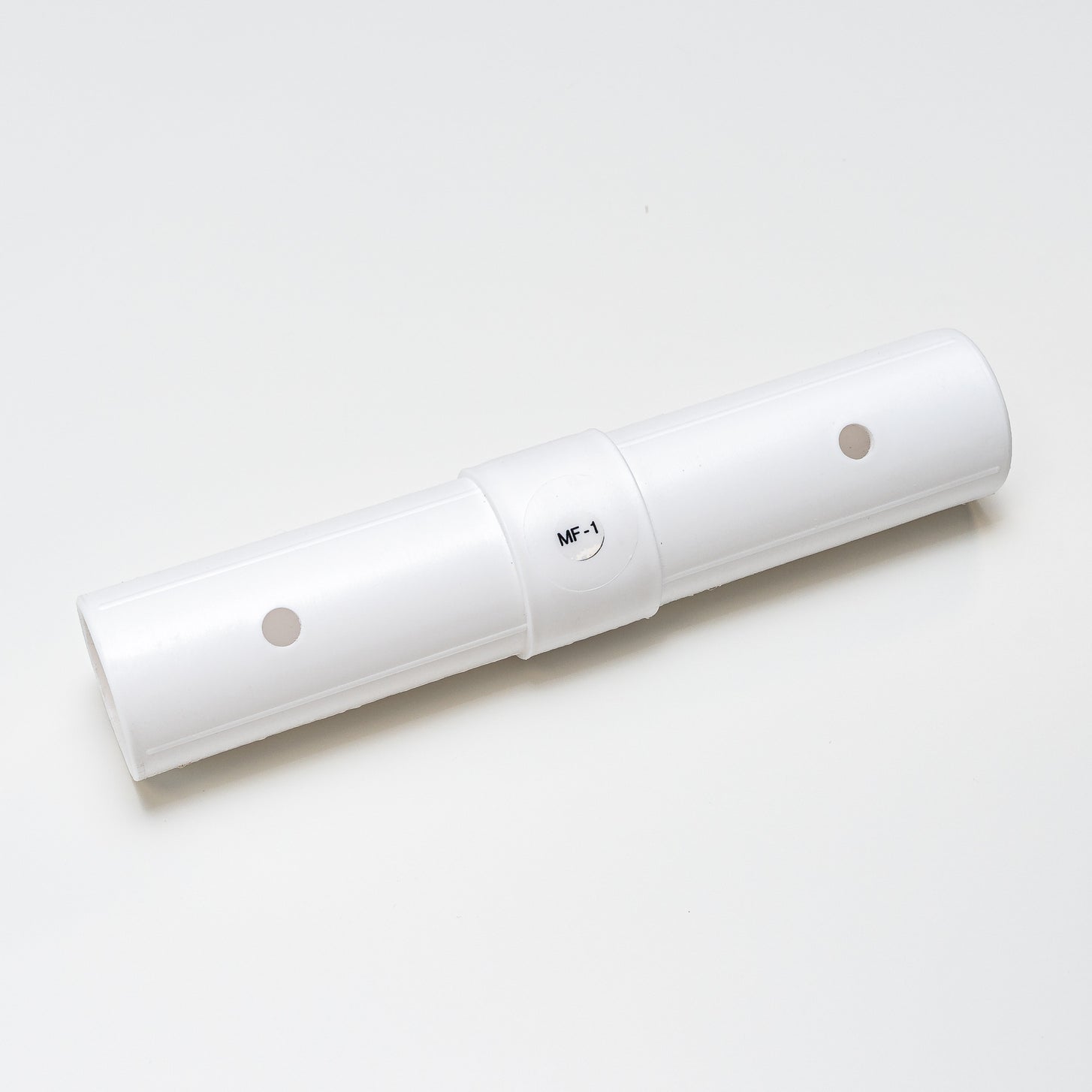 Q-FOLD MF1 tube: a straight white plastic tube connector marked MF-1, with a small hole near each end, on a white background.