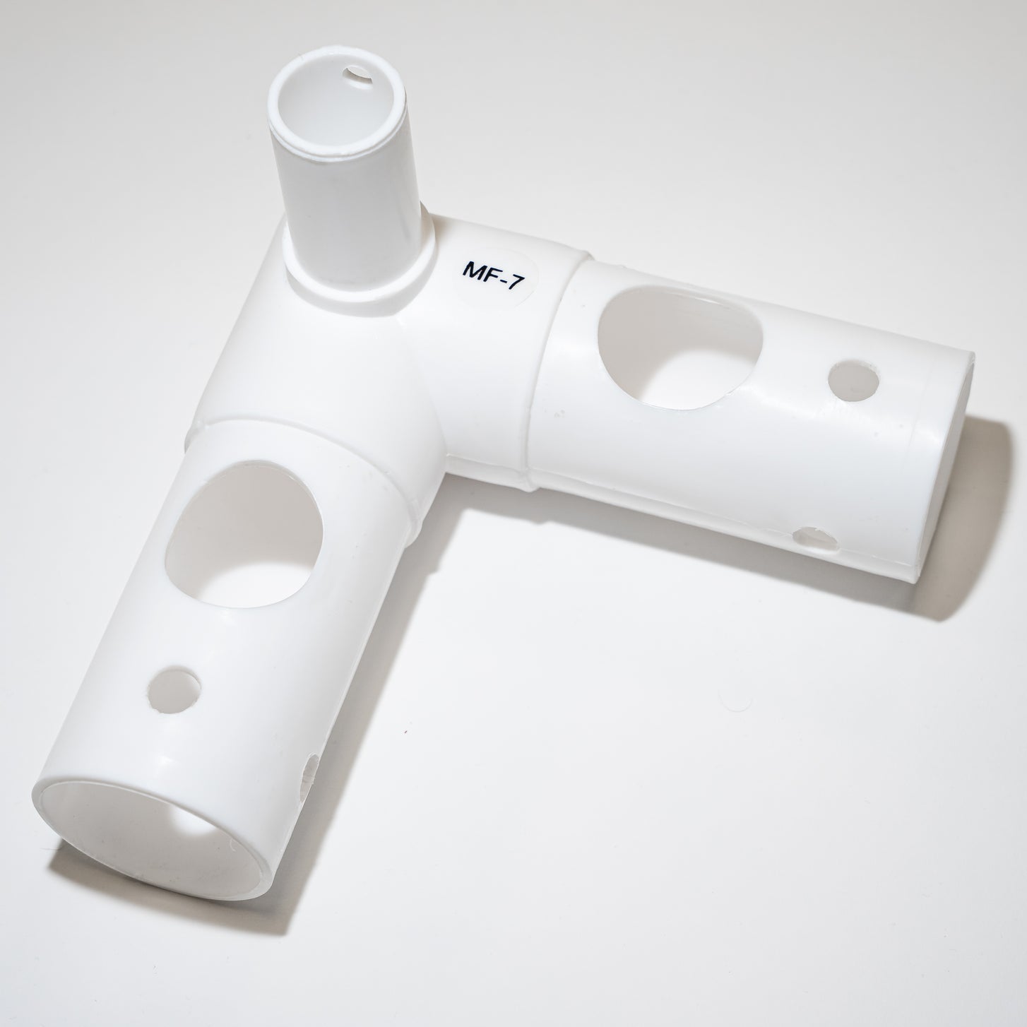 White Q-FOLD Match MF7 L-shaped joint tube with an upright spigot and round holes, labeled MF-7, on a white background.