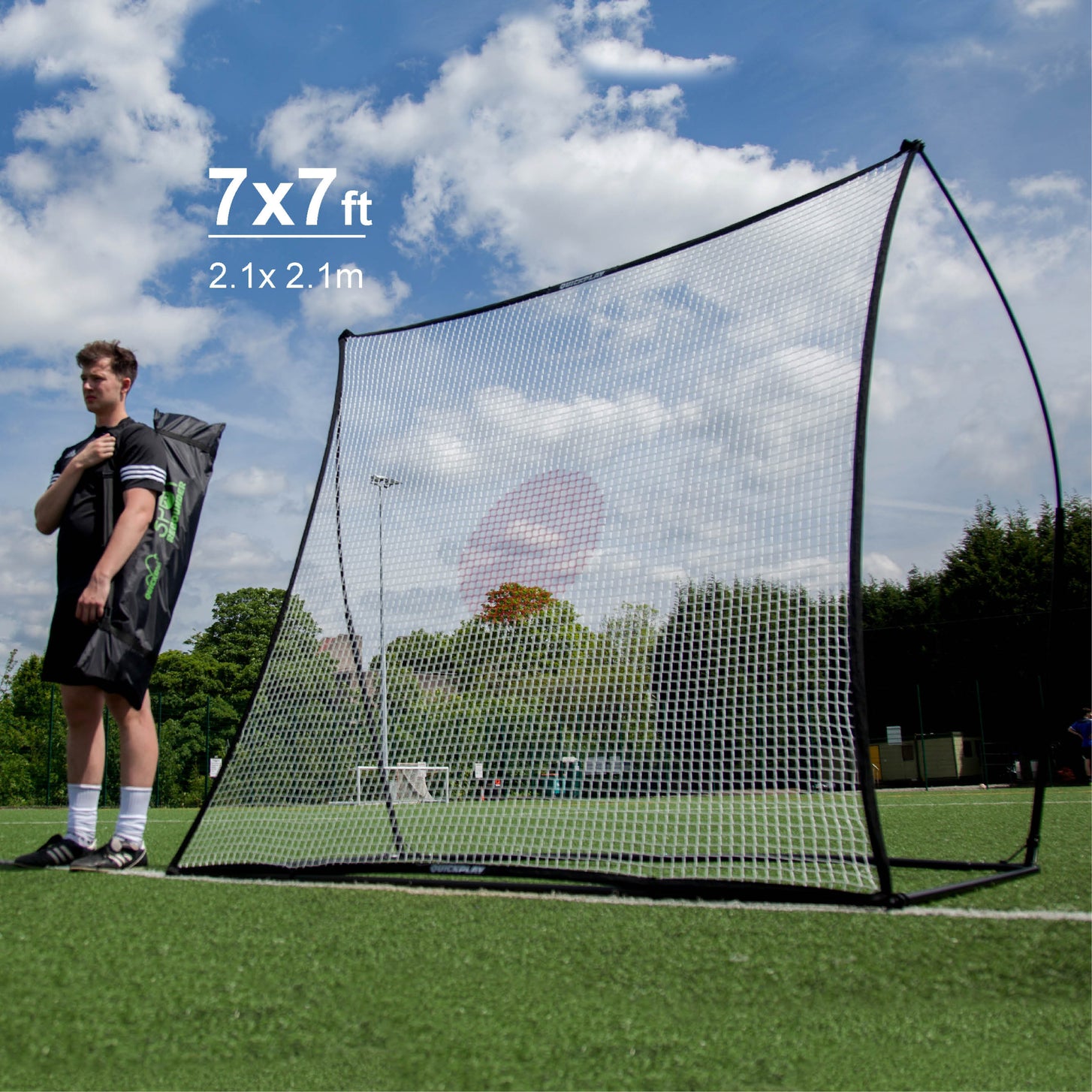 SPOT Soccer Rebounder 7x7' on an artificial field next to a player carrying a black bag, marked "7x7ft, 2.1x2.1m".