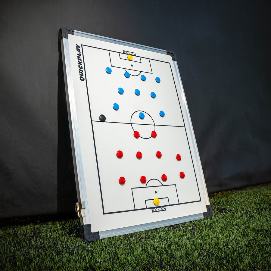 Magnetic soccer tactics board with red and blue markers on a grass field