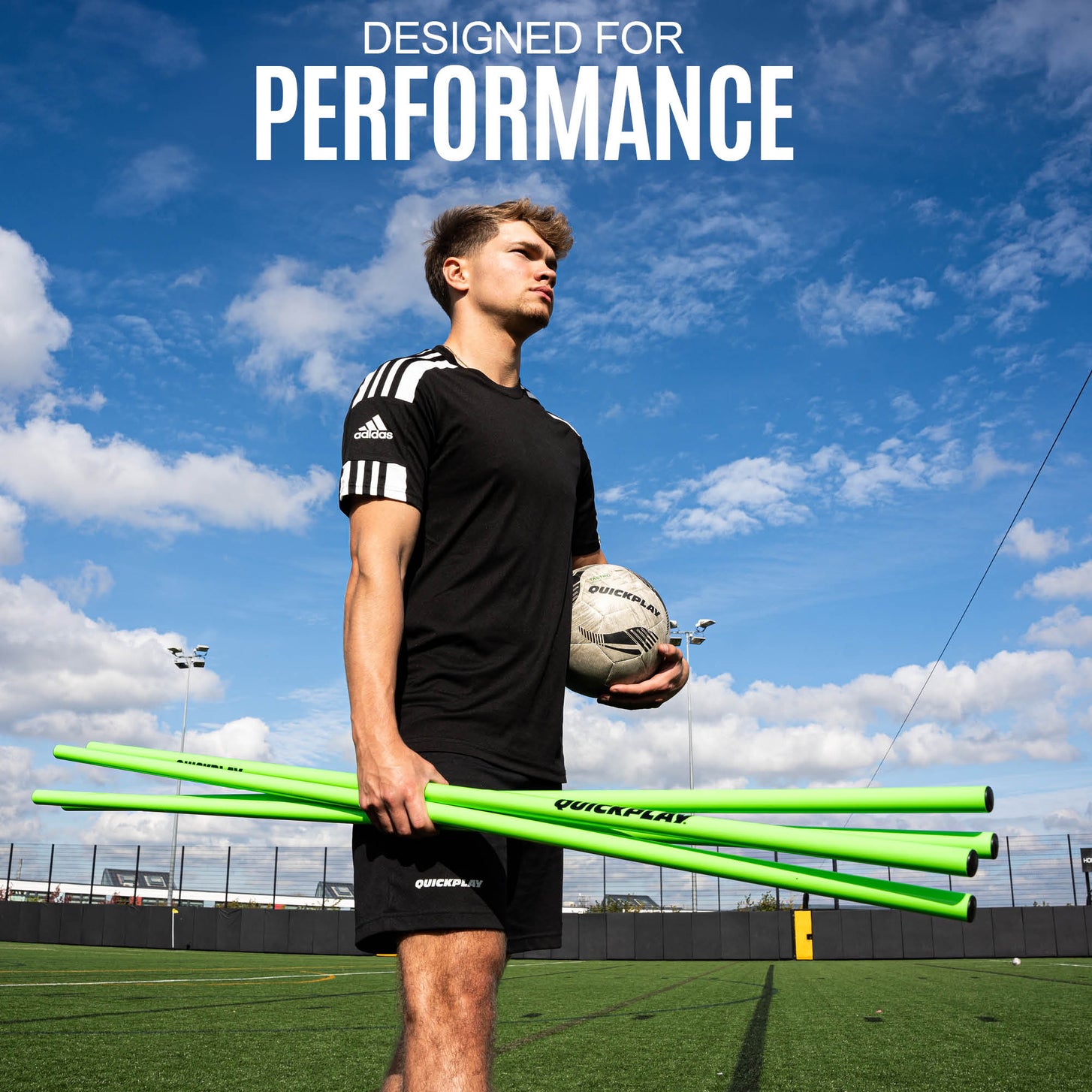 Player holding green Training Poles and a soccer ball on an artificial field, with the text "Designed for performance".