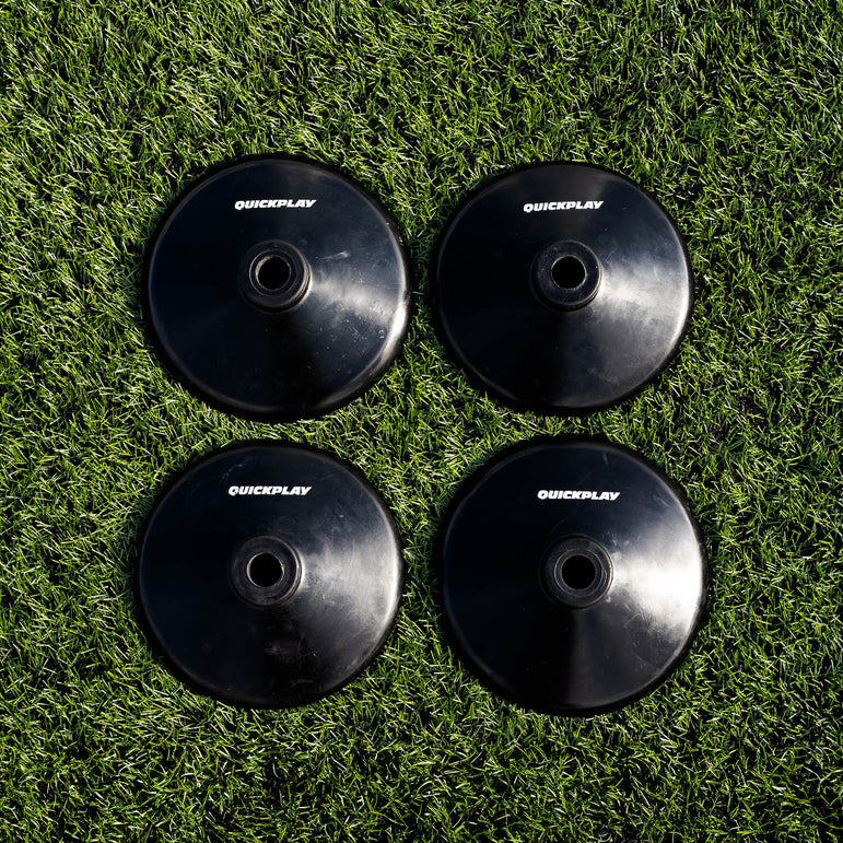 Four black training pole bases with 'QuickPlay' branding on a grass field.