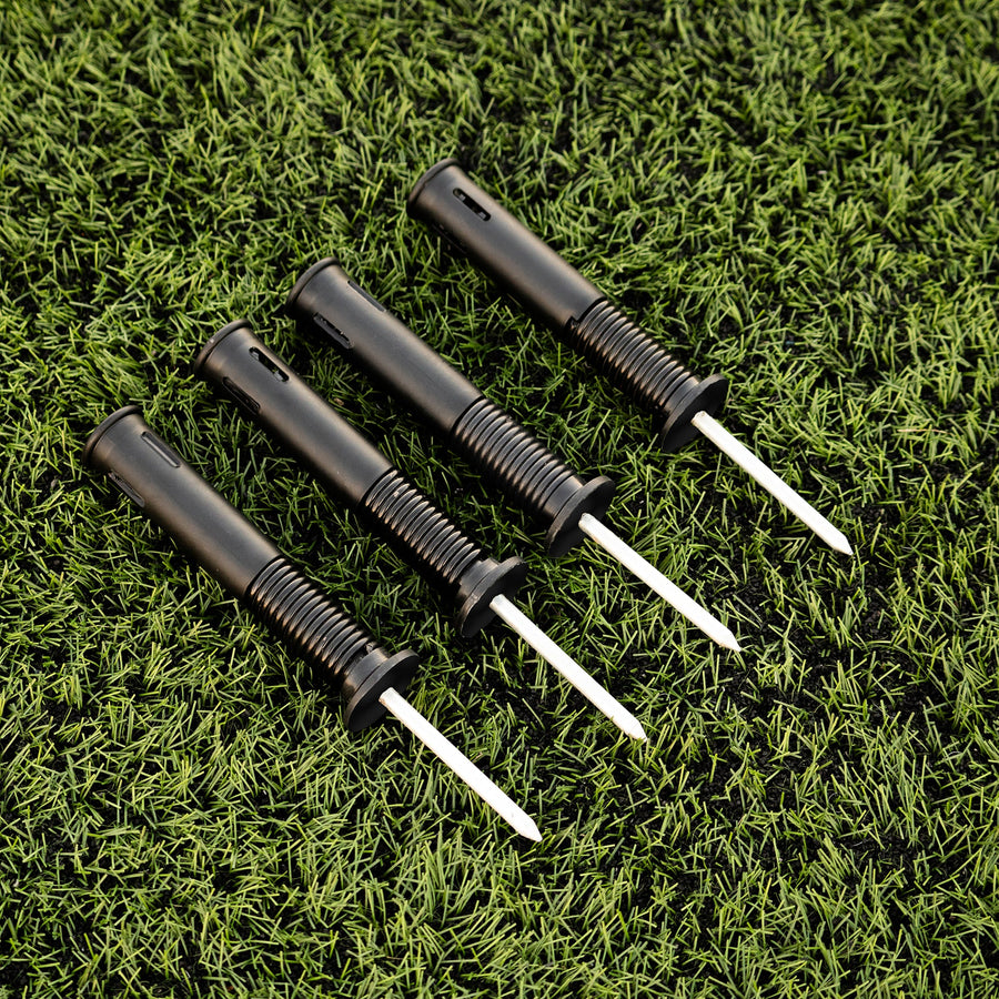 Four black sprung ground stakes on a green grass background