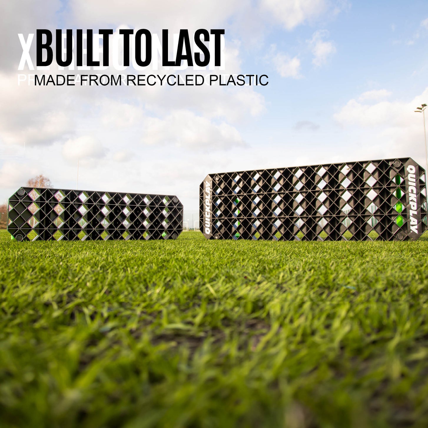 Two REPLAY Station XL boards seen from ground level on a grass field, with the text "Built to last, made from recycled plastic".