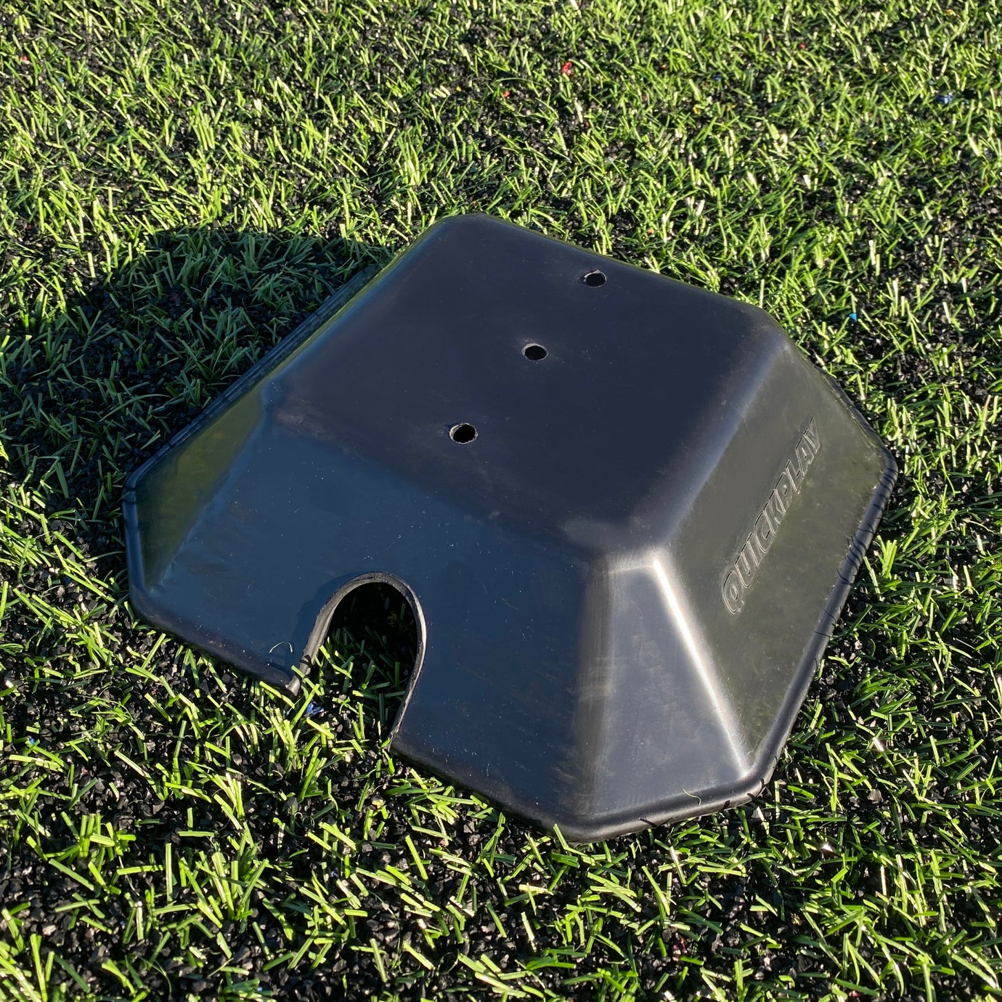 Base Weight for KICKSTER, SPOT & Agility Poles: one black QUICKPLAY weight on artificial turf, with three holes on top and a side cutout.