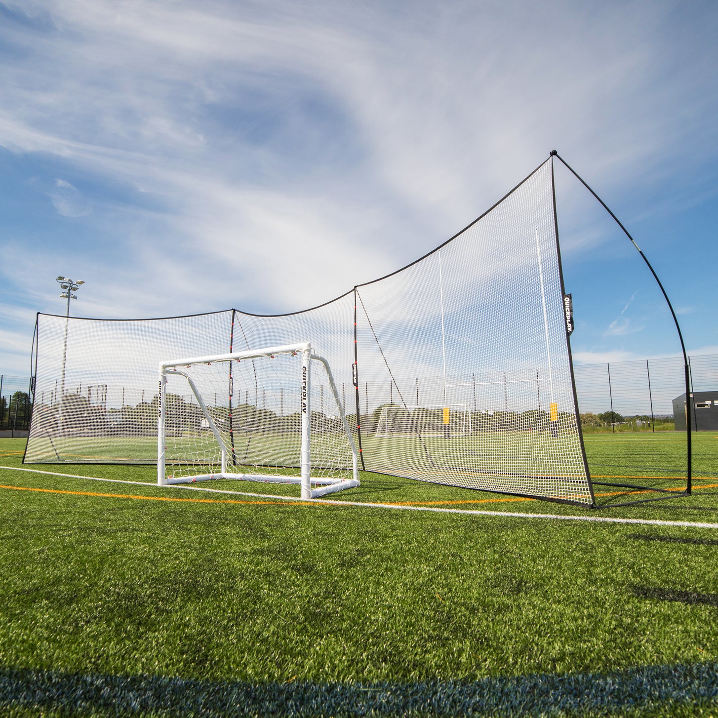 MEGA NET XL Multi Sport Backstop Net 32x9' set up behind a white soccer goal on an artificial field.