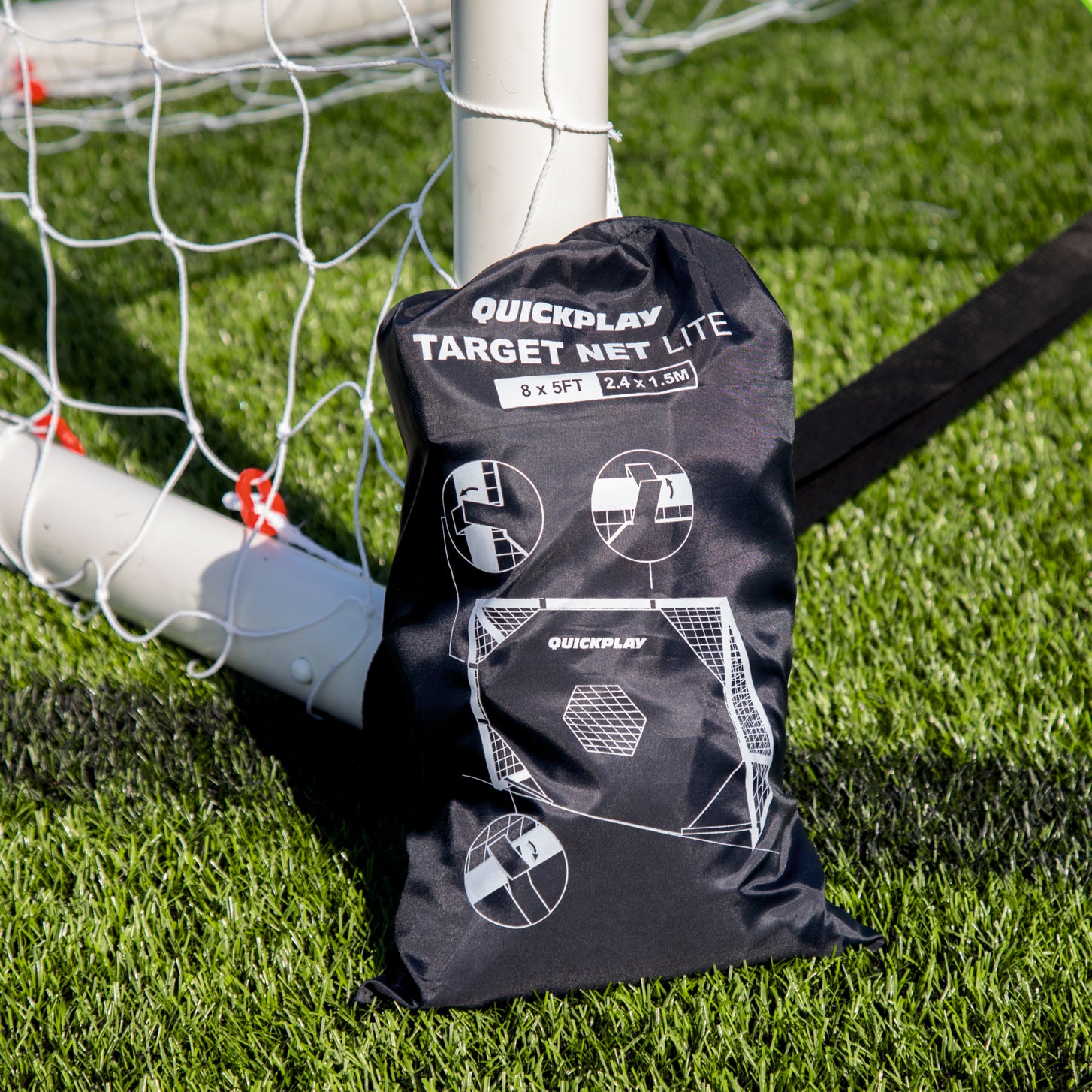 TARGET Net Lite 6x4' packed in its black QUICKPLAY drawstring bag, leaning against a white goal post on artificial turf
